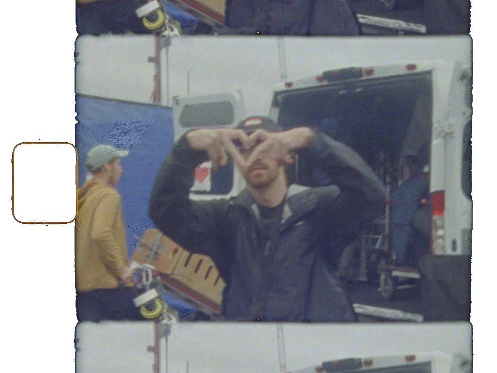 A man standing in front of an open cargo van making a peace sign with both hands.
