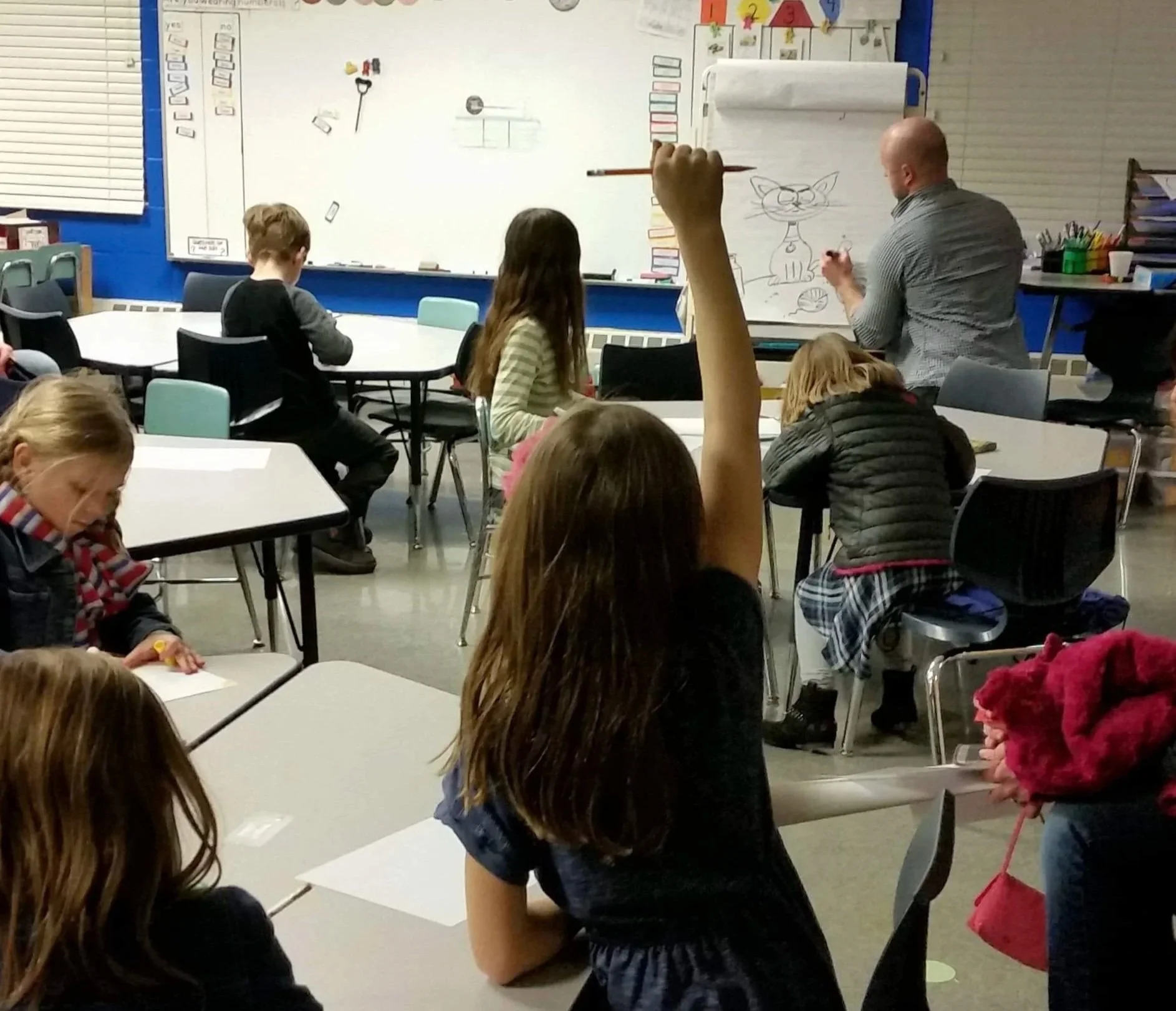 Greg drawing in classroom while girl raises her hand
