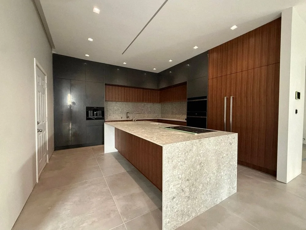 Custom modern kitchen in Vancouver with walnut cabinetry, large island, and pendant lighting by Alpha BC Woodcrafts