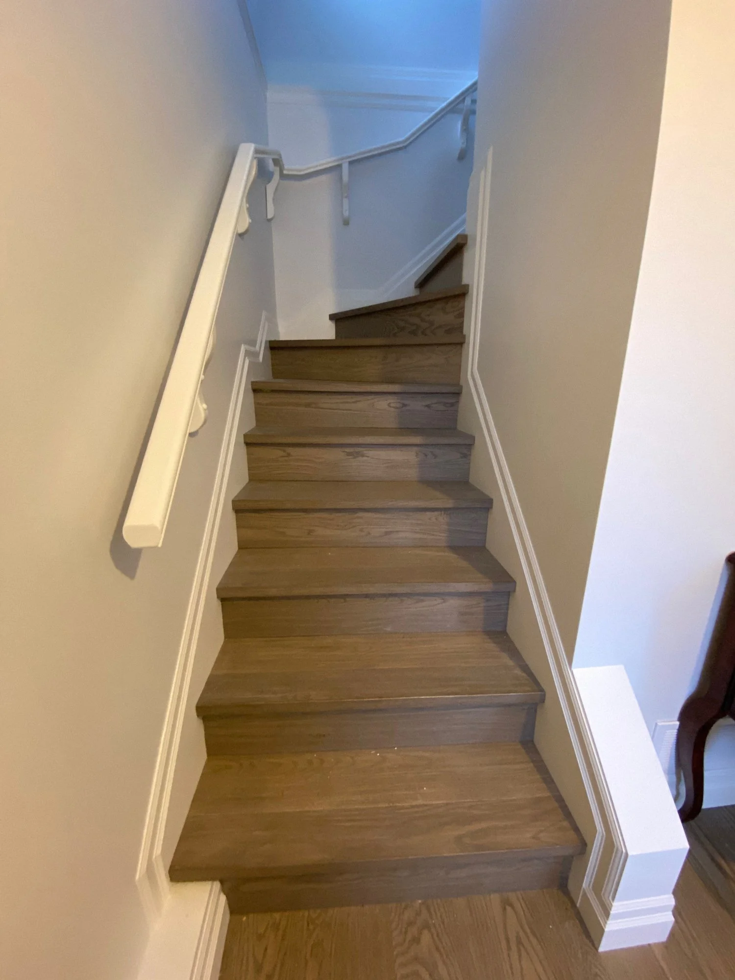 Custom wood staircase with white handrail in a residential home in Vancouver, BC by Alpha Woodcrafts