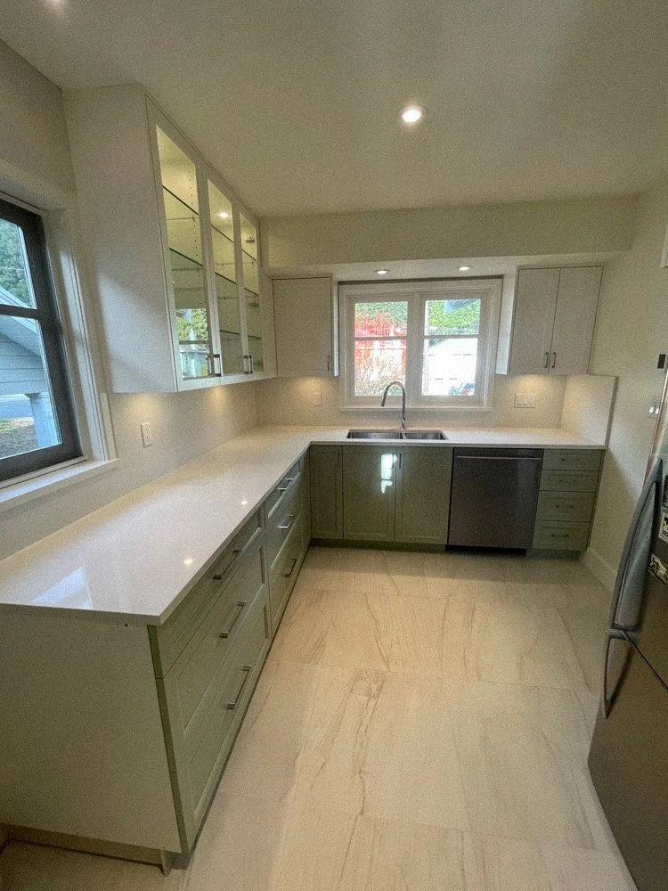 Custom kitchen millwork in North Vancouver featuring soft green cabinetry, quartz countertops, and integrated storage by Alpha Woodcrafts