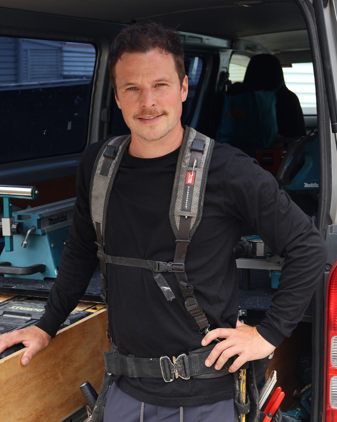 Chris Corless standing in front of his van ready for work with tools.