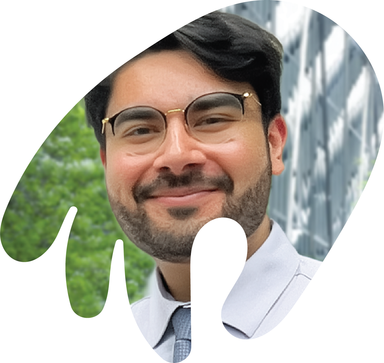 Faris Mahmood is smiling with closed lips. he has short black haired is wearing smart glasses with a black frame on the top half. behind him is an out of focus building and tree. The photo is cropped into the loose shape of a hand in action.