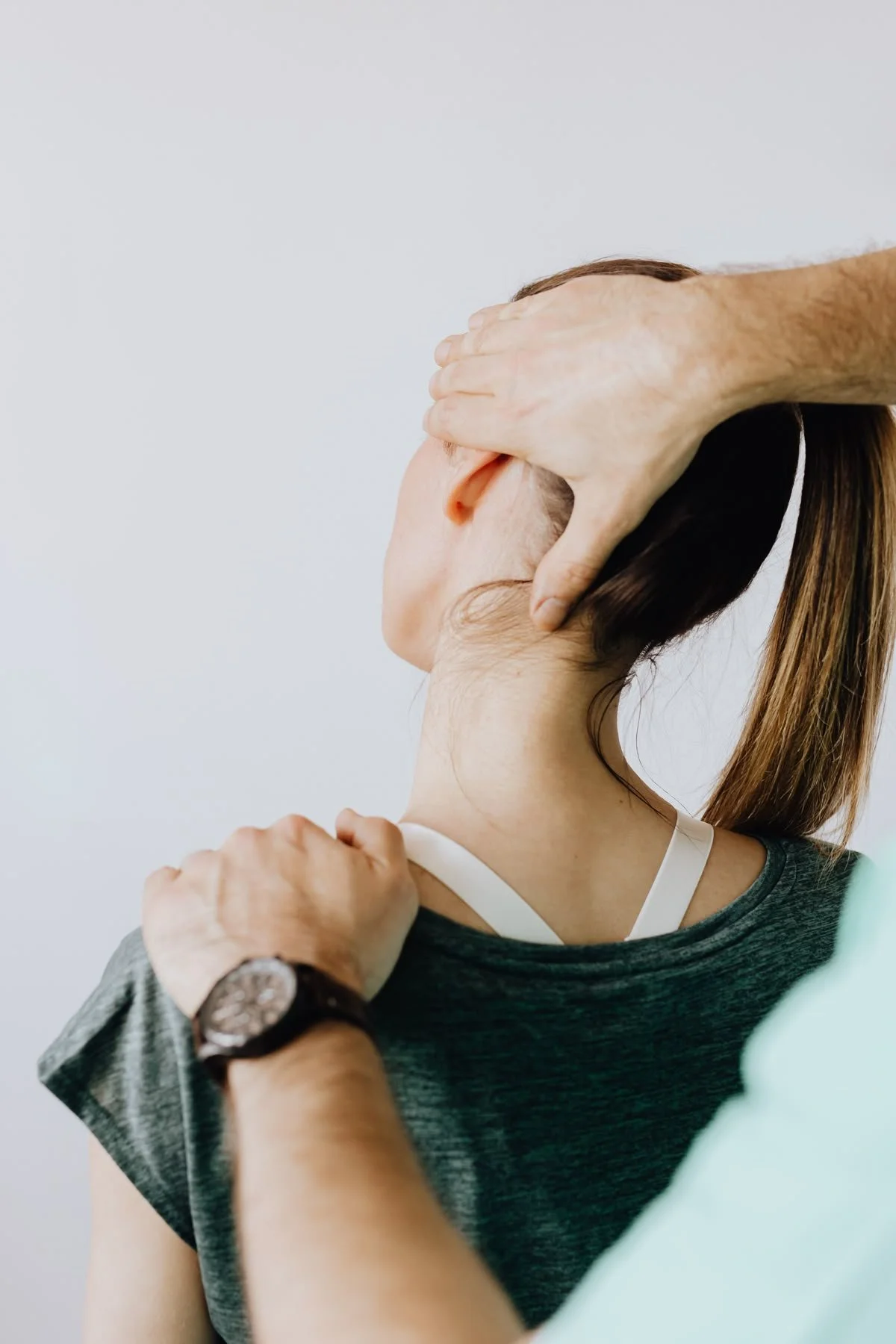 A person is receiving a neck massage from a professional therapist in a clinical setting.