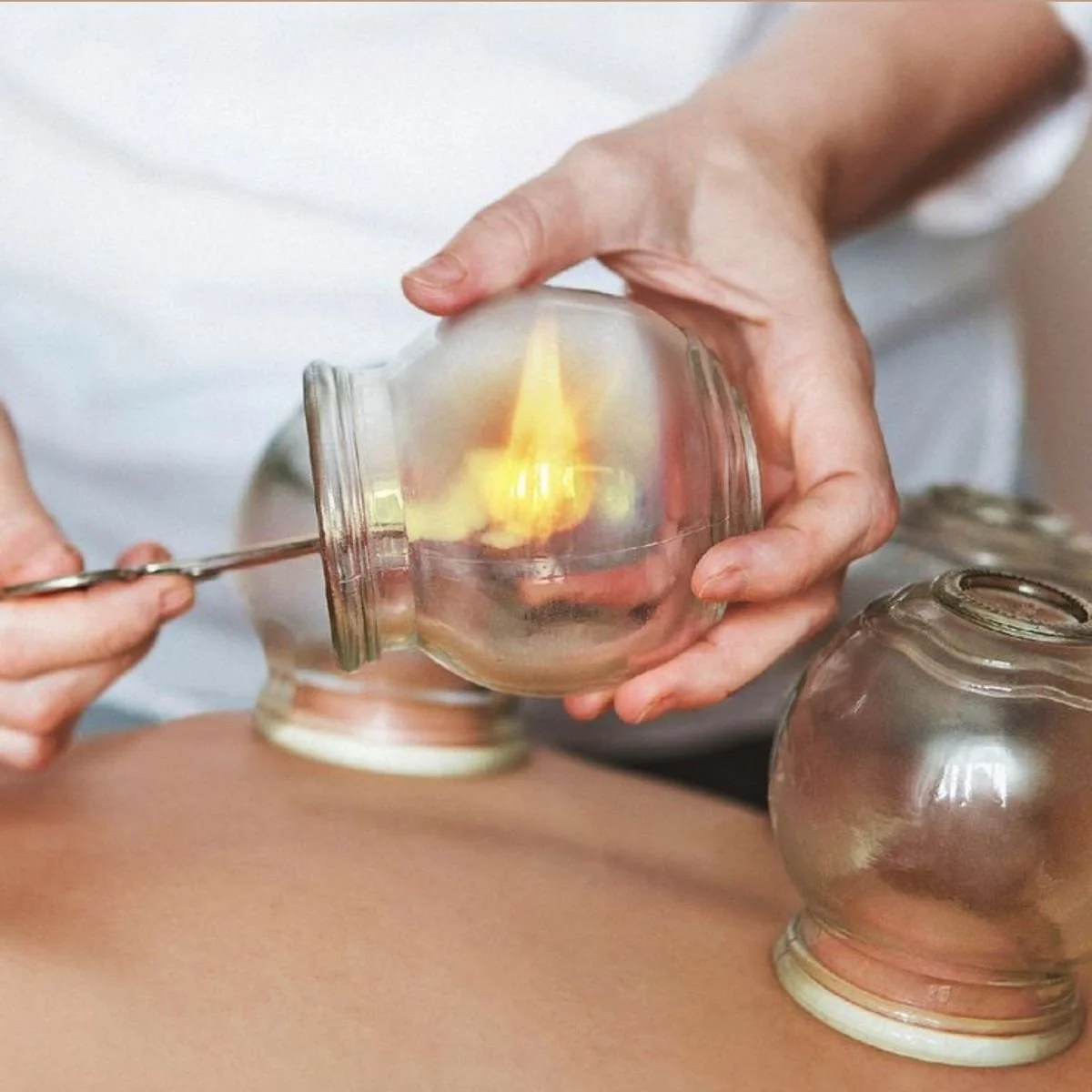 A person performing a glass blowing craft using a torch, with the flame directed into a glass piece.