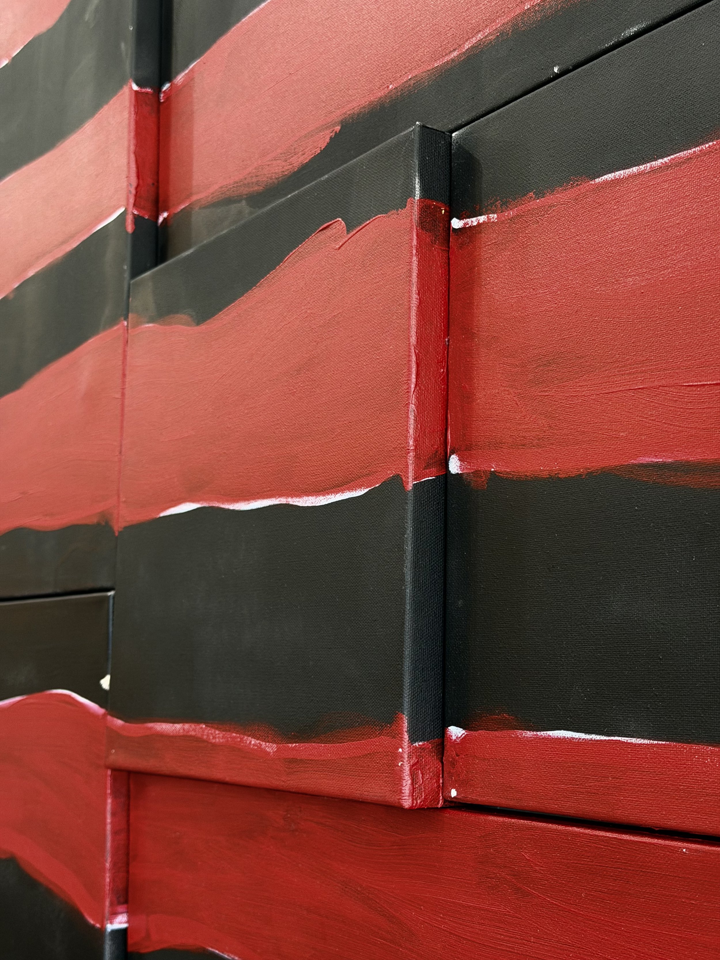 Close-up of a red and black painted object with visible paint strokes and a corner where two panels meet.