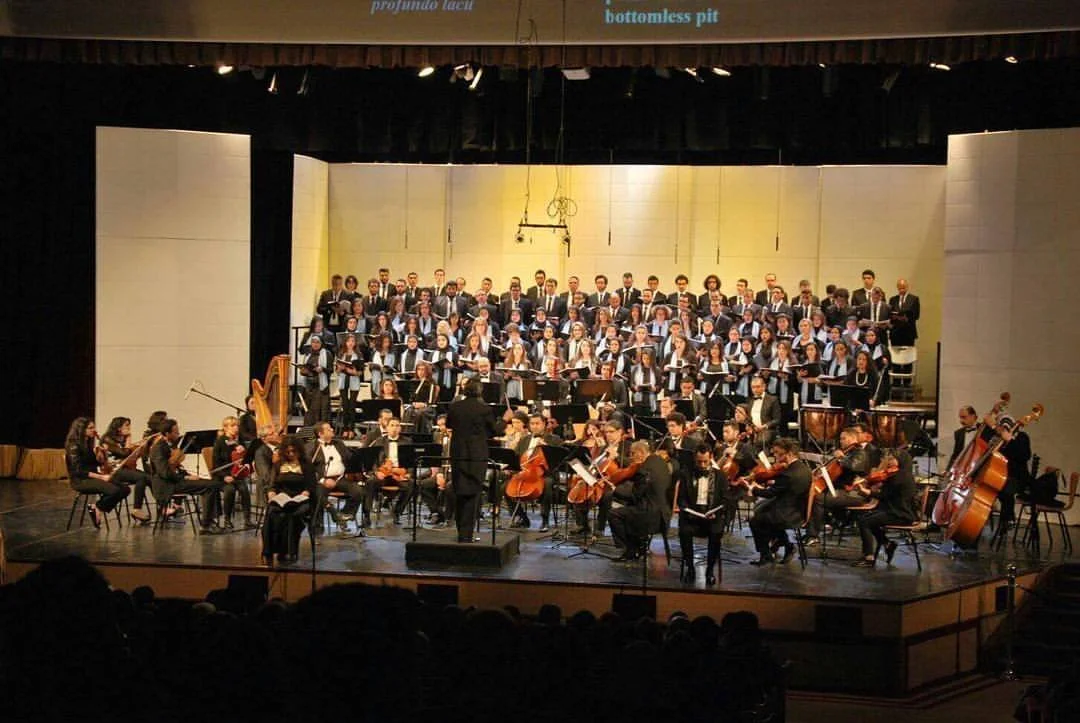 Orchestra and choir performing on stage in a concert hall.