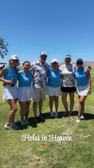 Group of six women and one man standing on a golf course under a clear blue sky, wearing golf attire, with a small golf hole with a flag in front of them, and the text "Holes in Heaven" at the bottom.