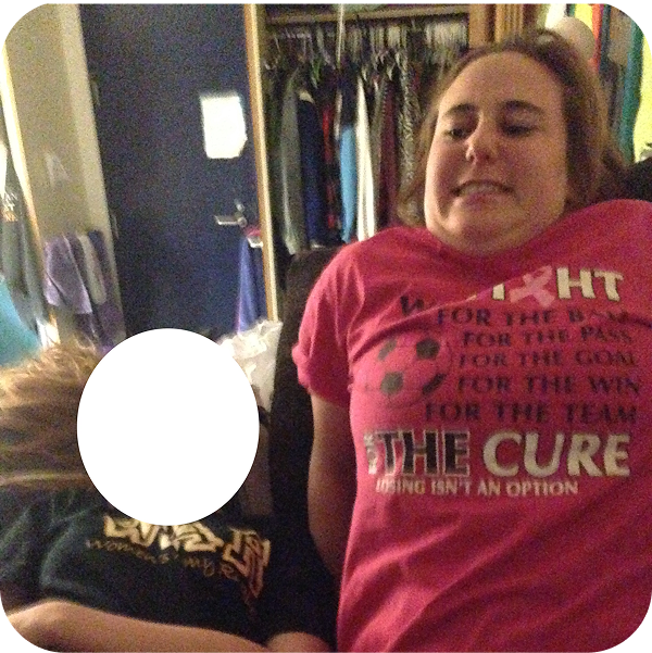 Two people sitting close together in a room with a closet in the background, with one person smiling and wearing a pink T-shirt and the other with a white circle obscuring their face.