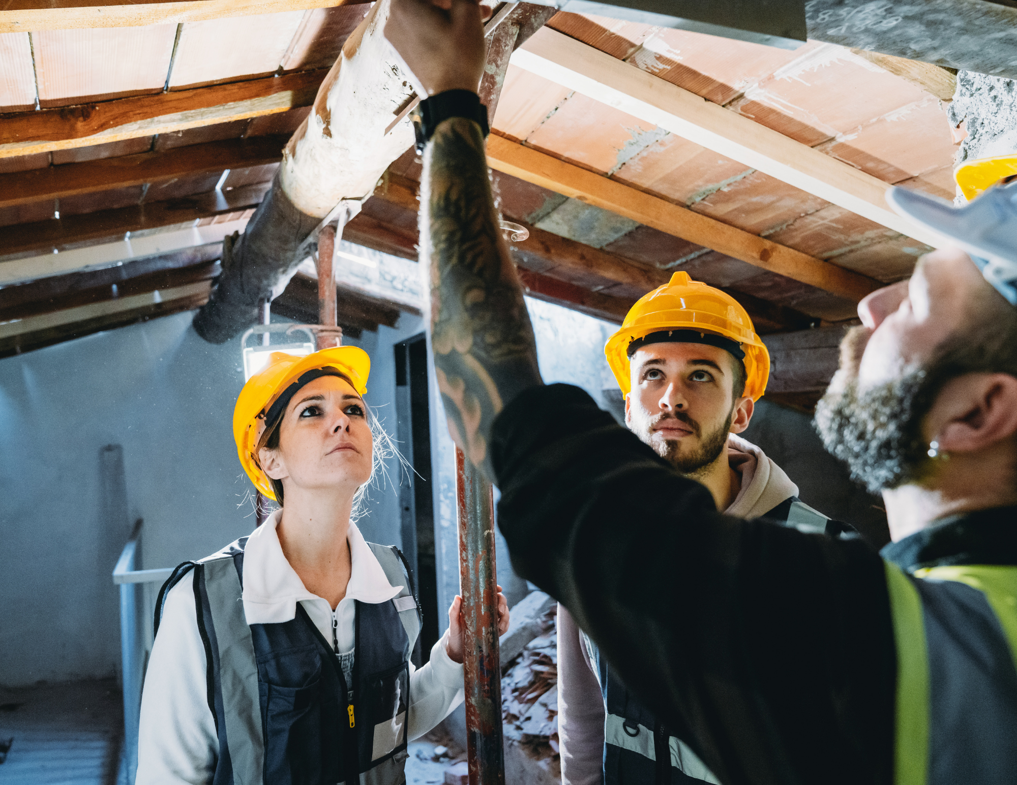 Group of construction workers wearing yellow safety helmets inspecting under a wooden ceiling