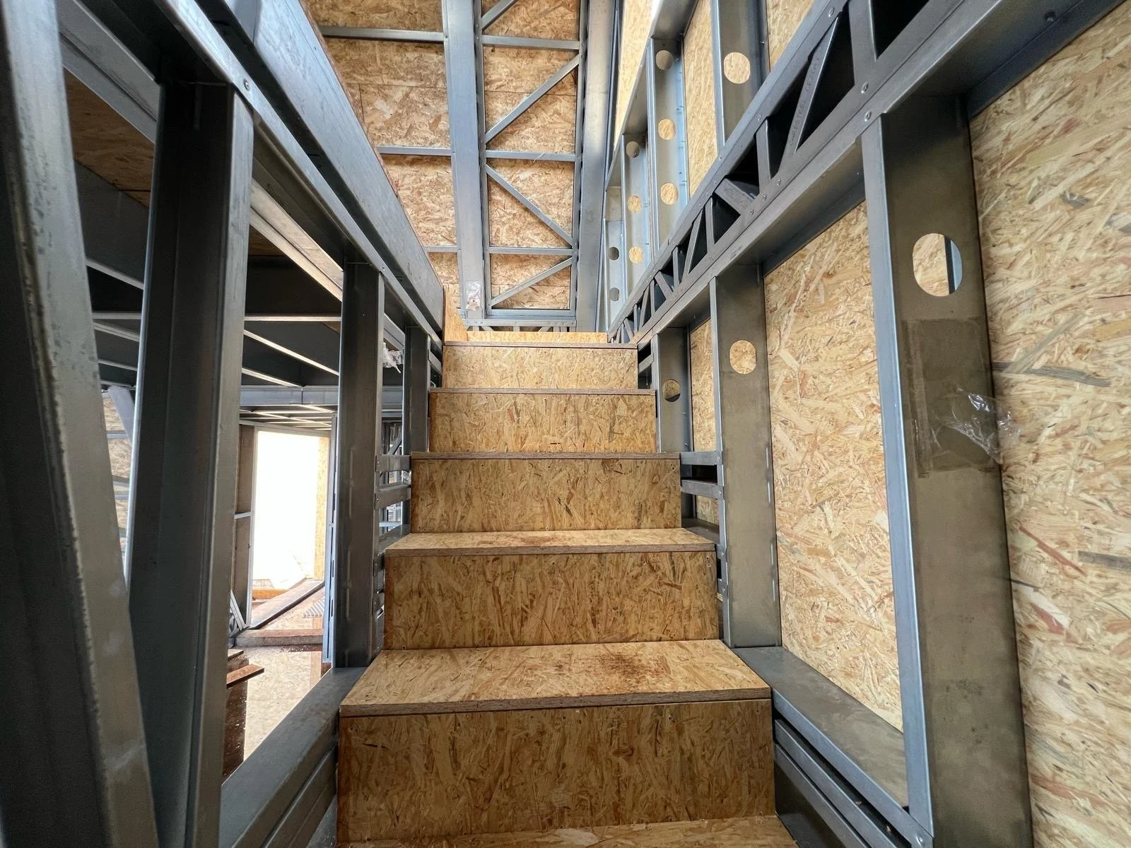Steel framing with wooden stairs under construction in a building.