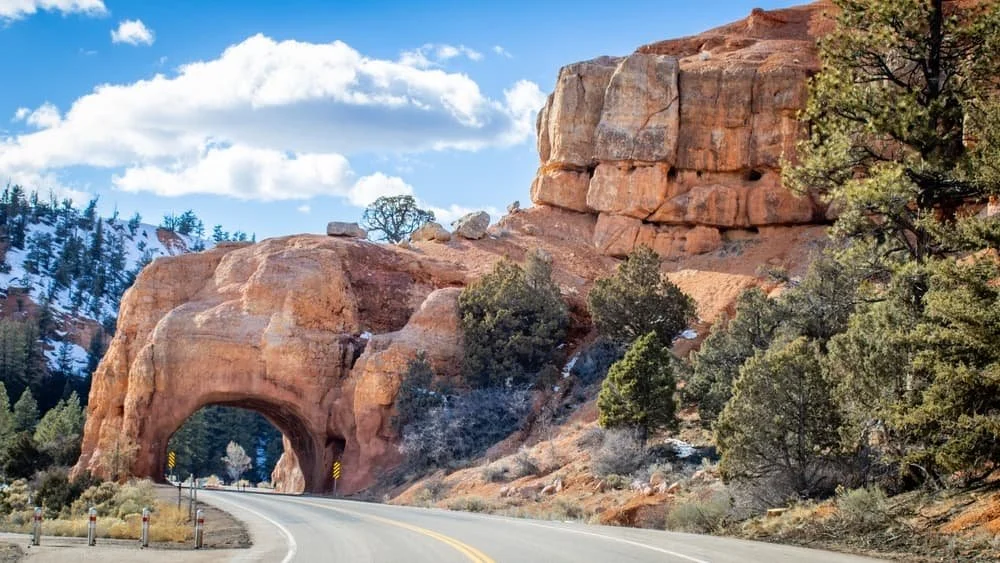 A road passes under a natural orange stone arch