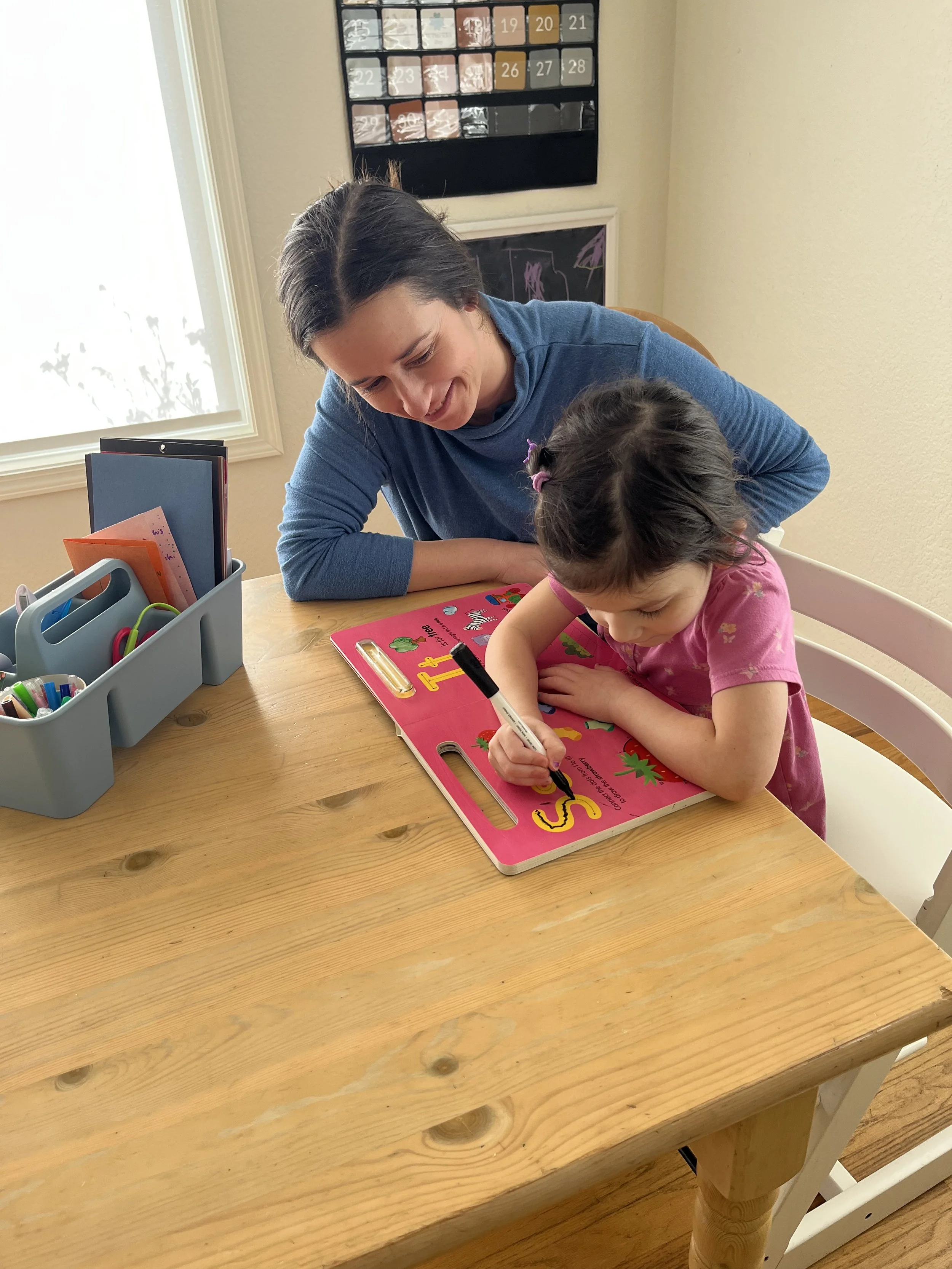 An occupational therapist working with a child, who is tracing a letter.