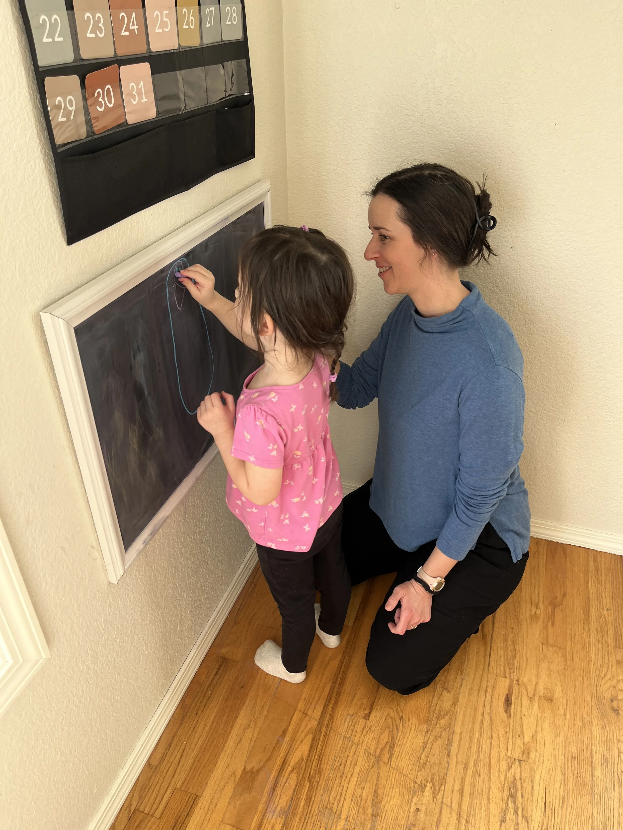 A child and occupational therapist drawing pictures on a chalkboard