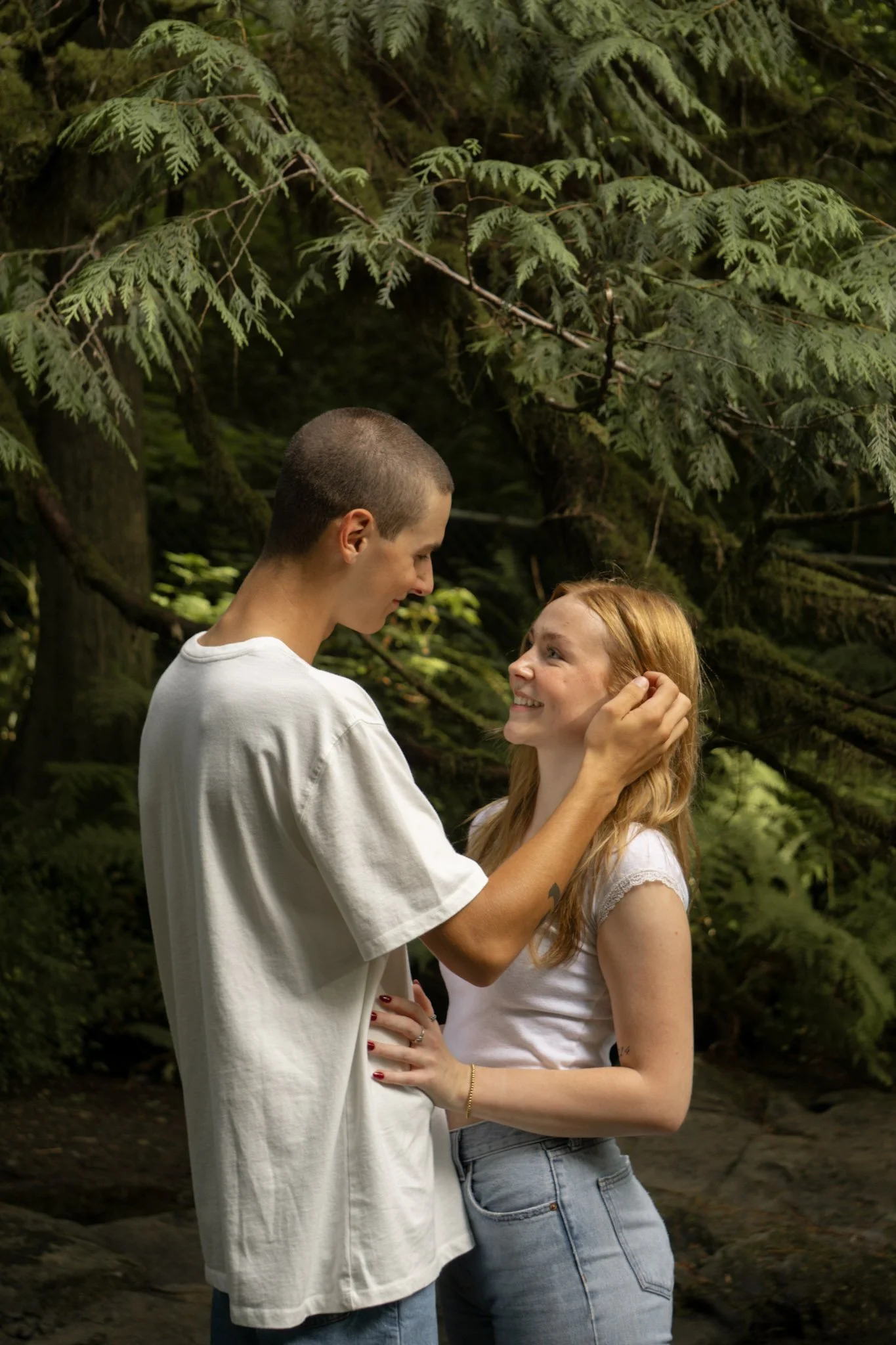 A couple being close together. The boy gently moves her hair behind her ear