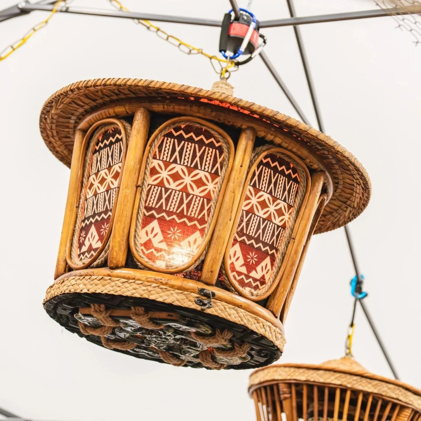 Three woven baskets with fabric linings decorated with red, black, and white tribal patterns hang from a ceiling.