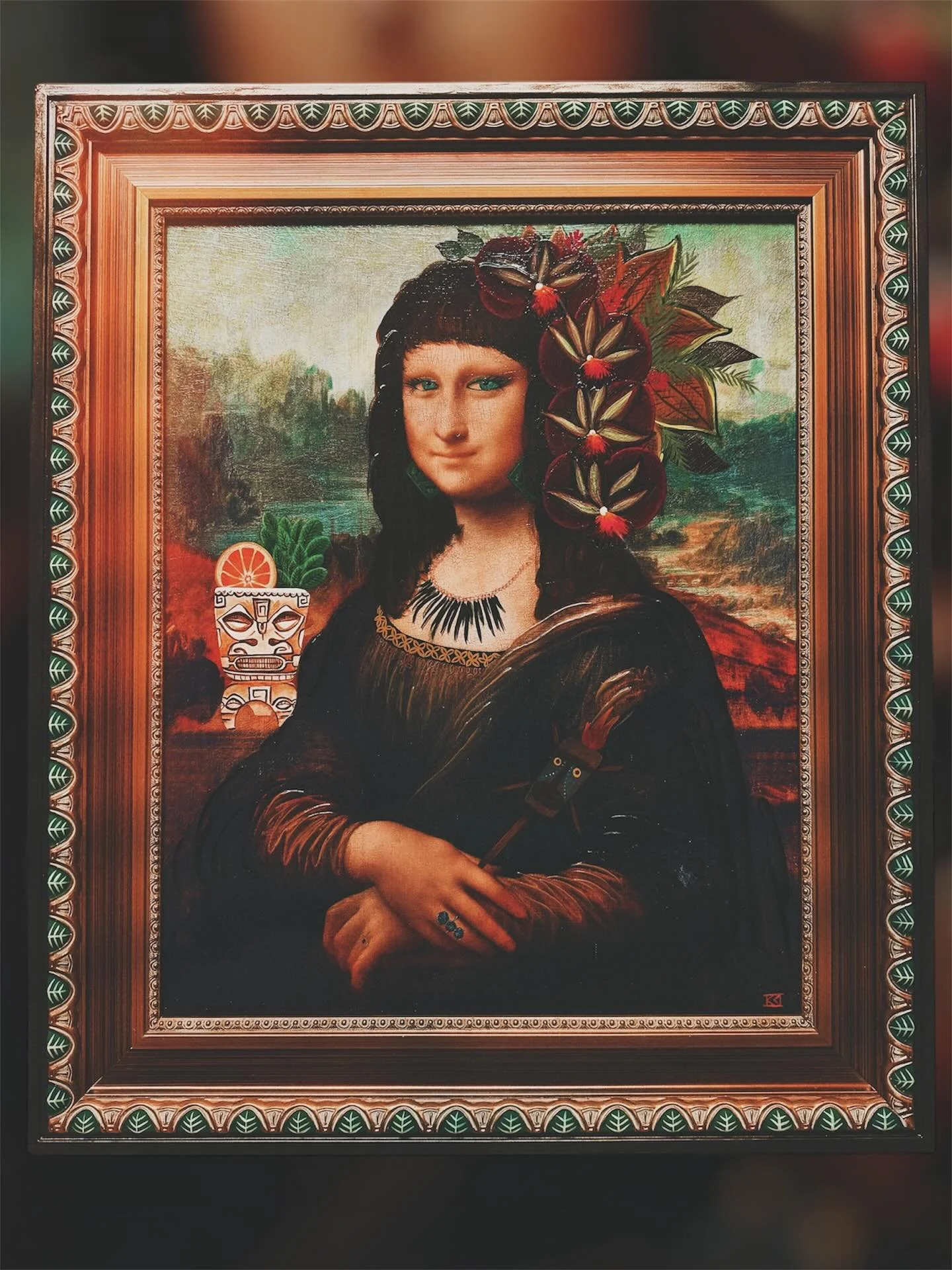 A framed painting of a woman with black hair, blue eyes, and a necklace, surrounded by tropical flowers and greenery.