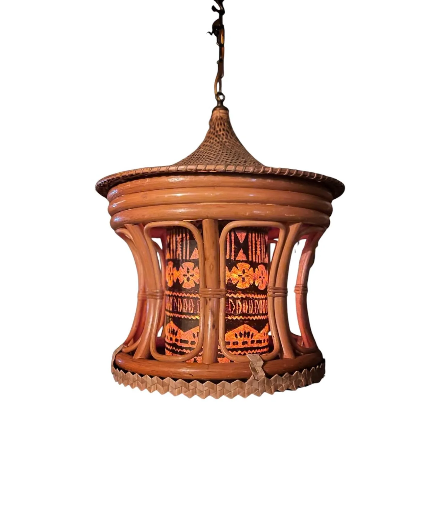 A wicker lantern with a floral and geometric pattern, holding a light source inside, hanging from a chain.