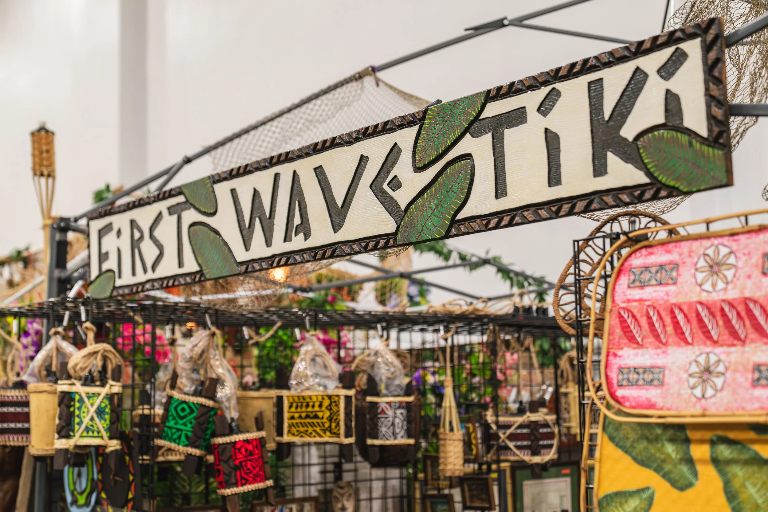 Display of North American Indigenous crafts and artwork at a market stall, including a sign with the word 'First Wavesti' and decorated items such as woven baskets, jewelry, and textiles.
