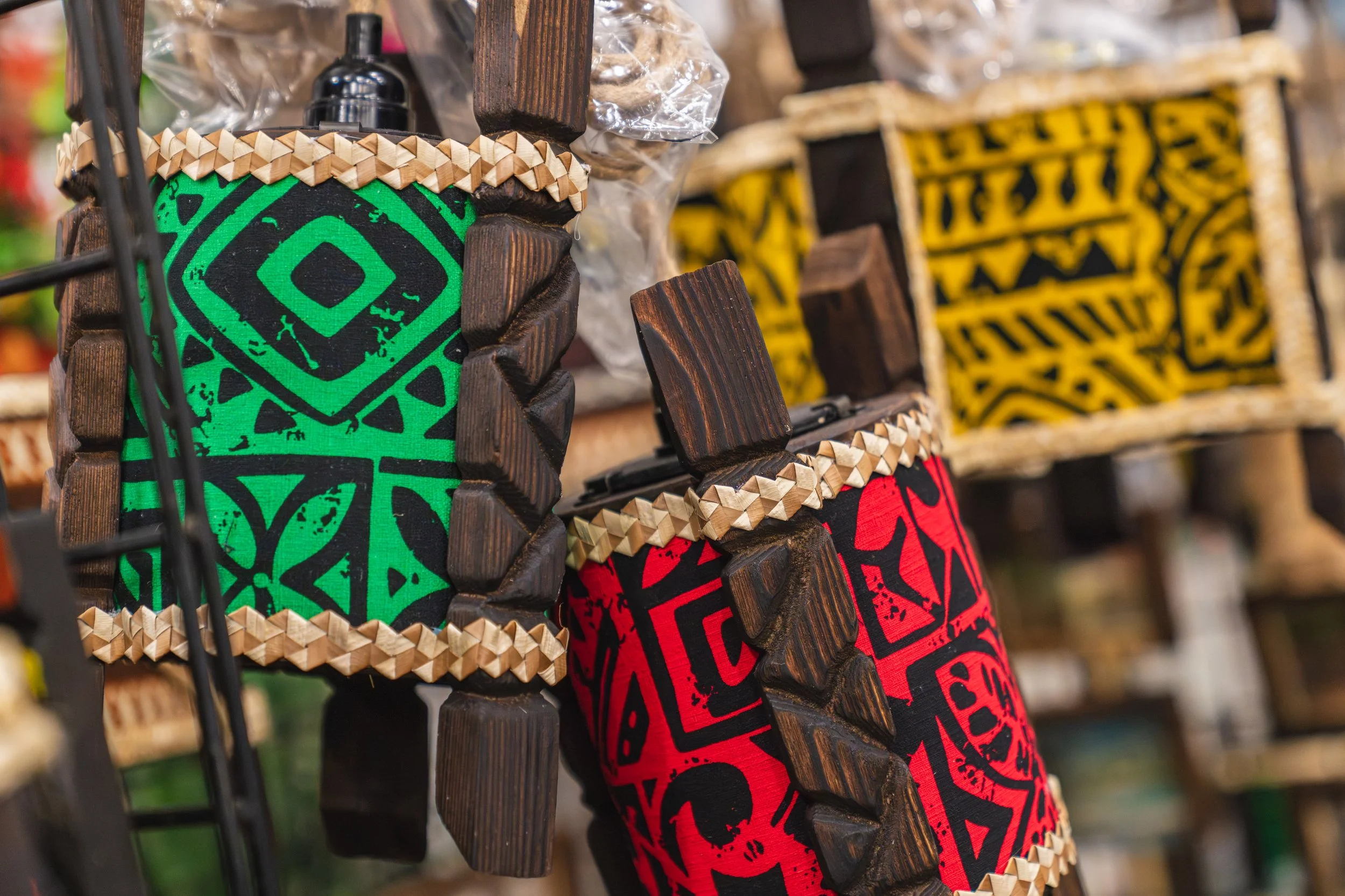 Colorful mugs with tribal patterns in green, red, and yellow, surrounded by wooden architectural elements and decorative woven trim.