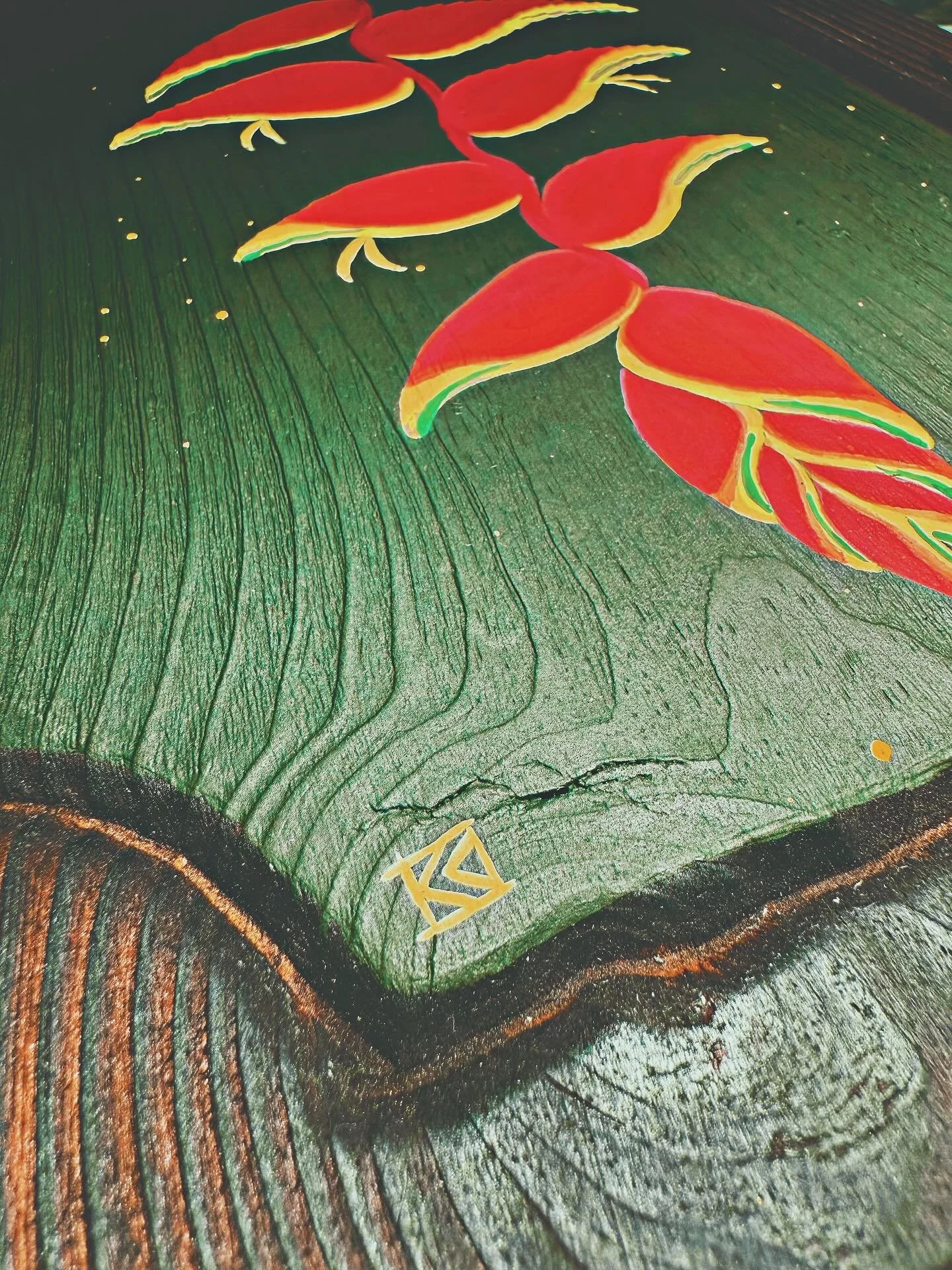 Close-up of a colorful leaf illustration with red, yellow, and green hues, accented by a gold geometric design at the bottom, on a textured dark background.