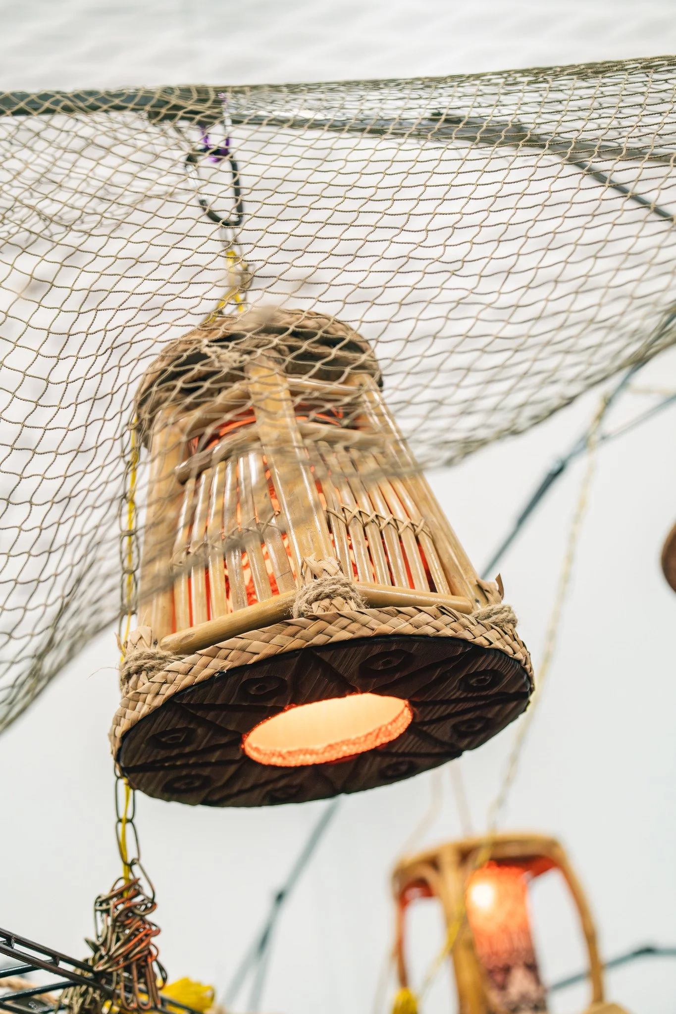 Close-up view of a traditional Chinese sky lantern made of bamboo and paper, with the lantern lit and glowing from inside, against a cloudy sky.