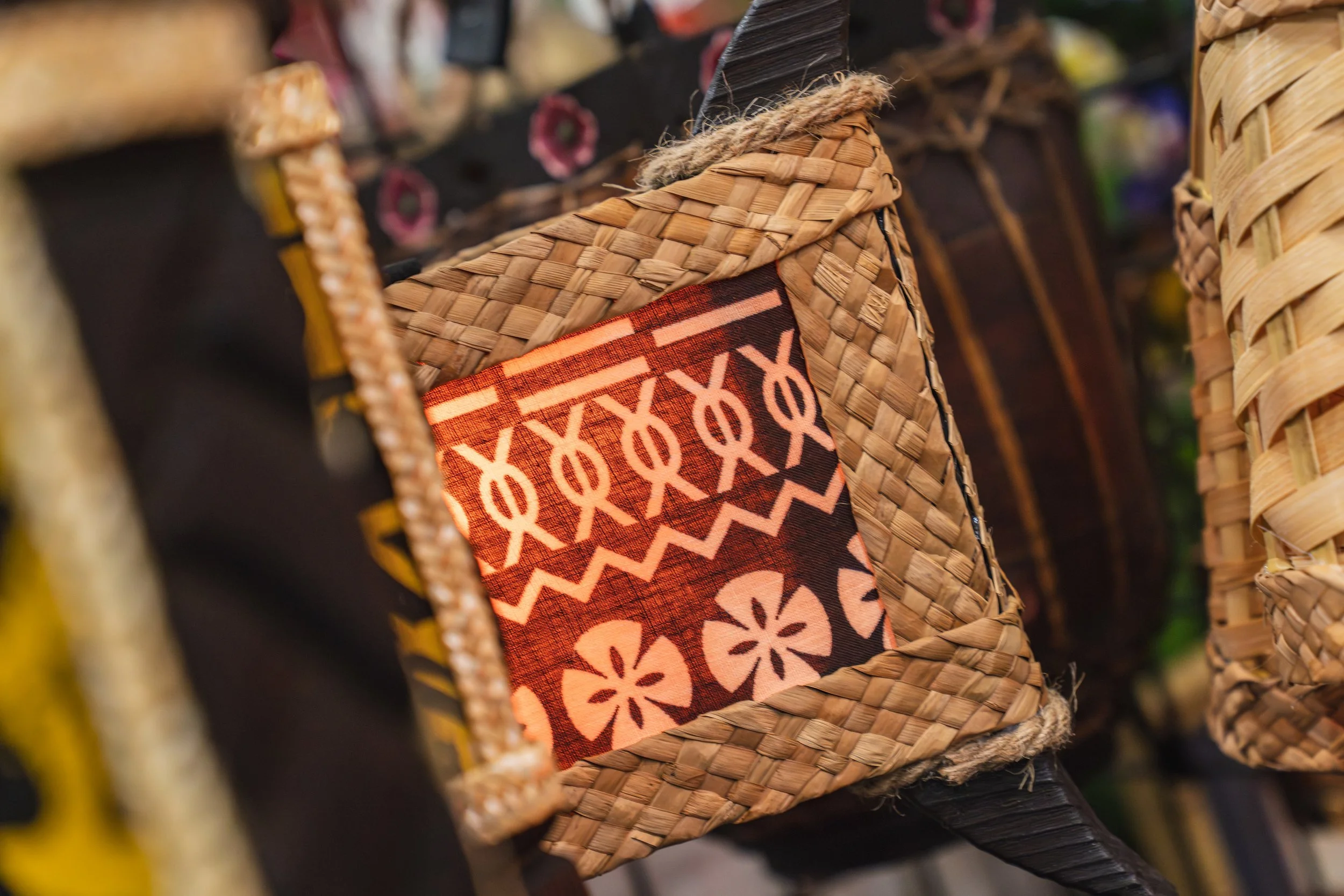 Close-up of woven baskets with a fabric piece featuring orange and white geometric patterns, displayed in a store.