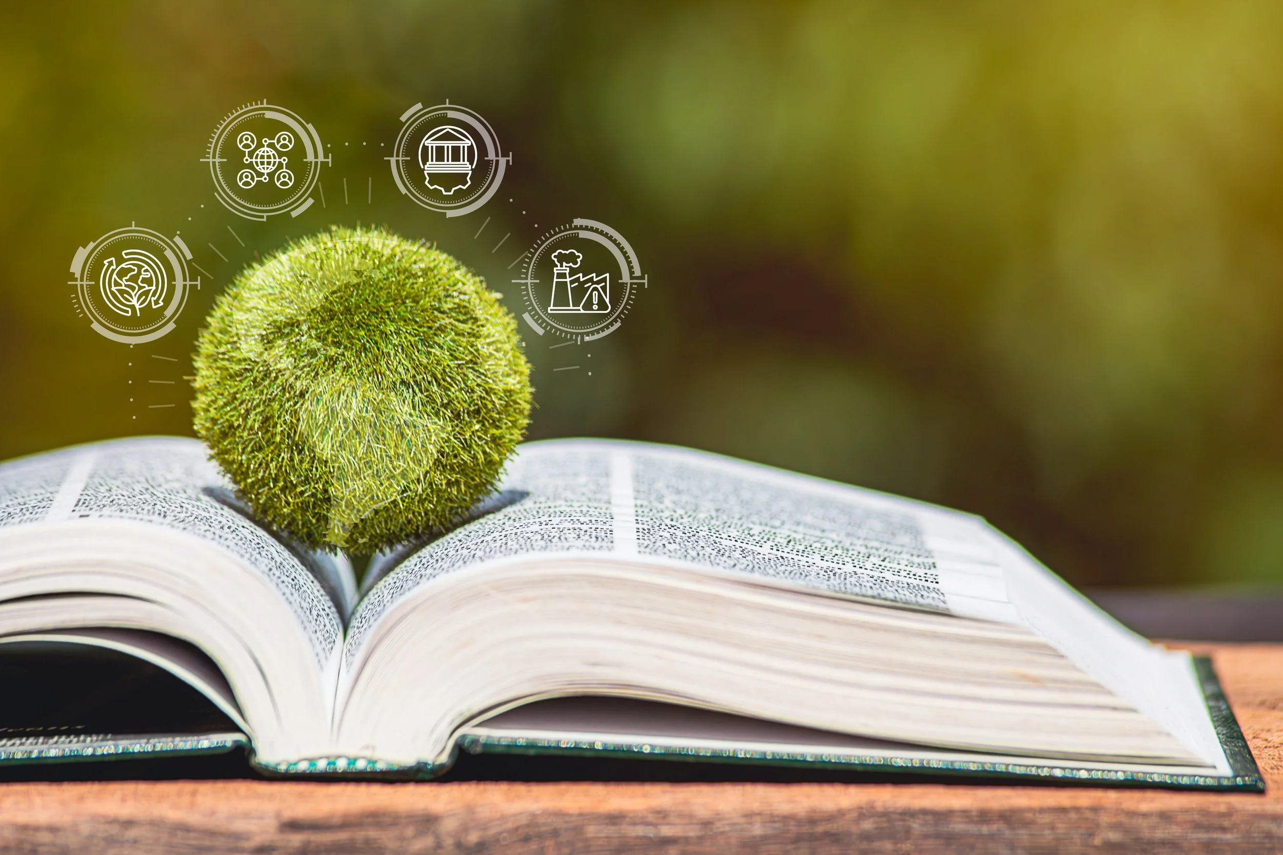 An open book with a fuzzy green moss sphere on top, and digital icons related to environment, industry, and community overlaid.