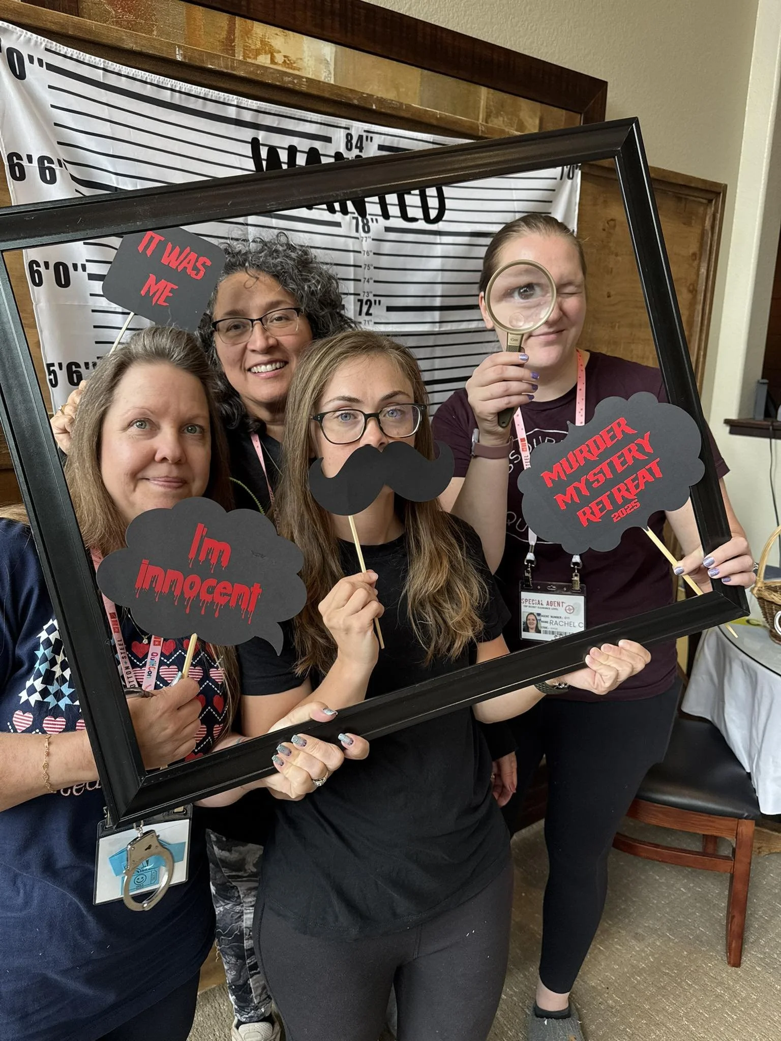 A group of women pose with photo booth props from the Fall sewing retreat. They're smiling.