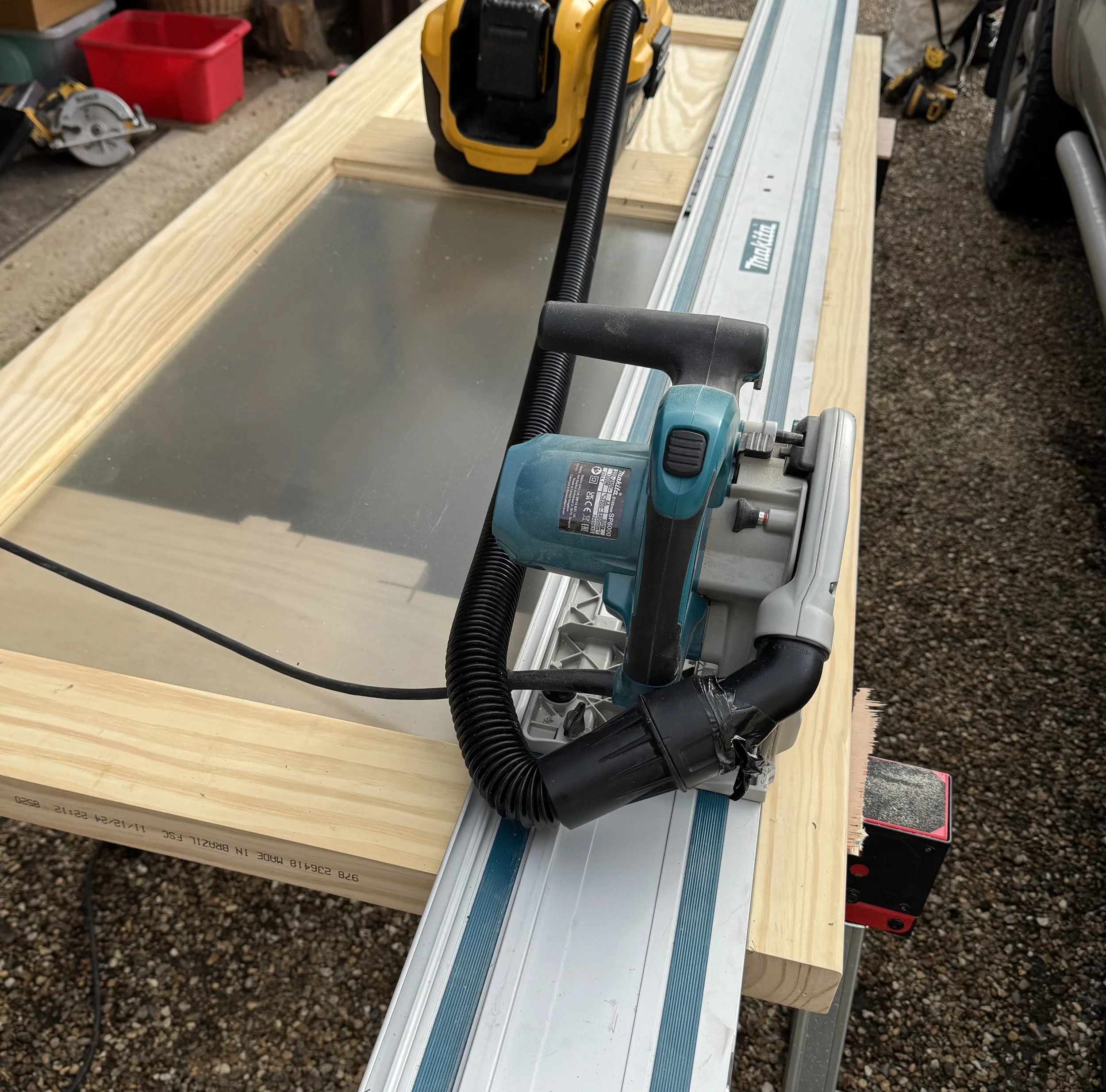 A power planer and vacuum hose on a workbench with wood and tools in the background.