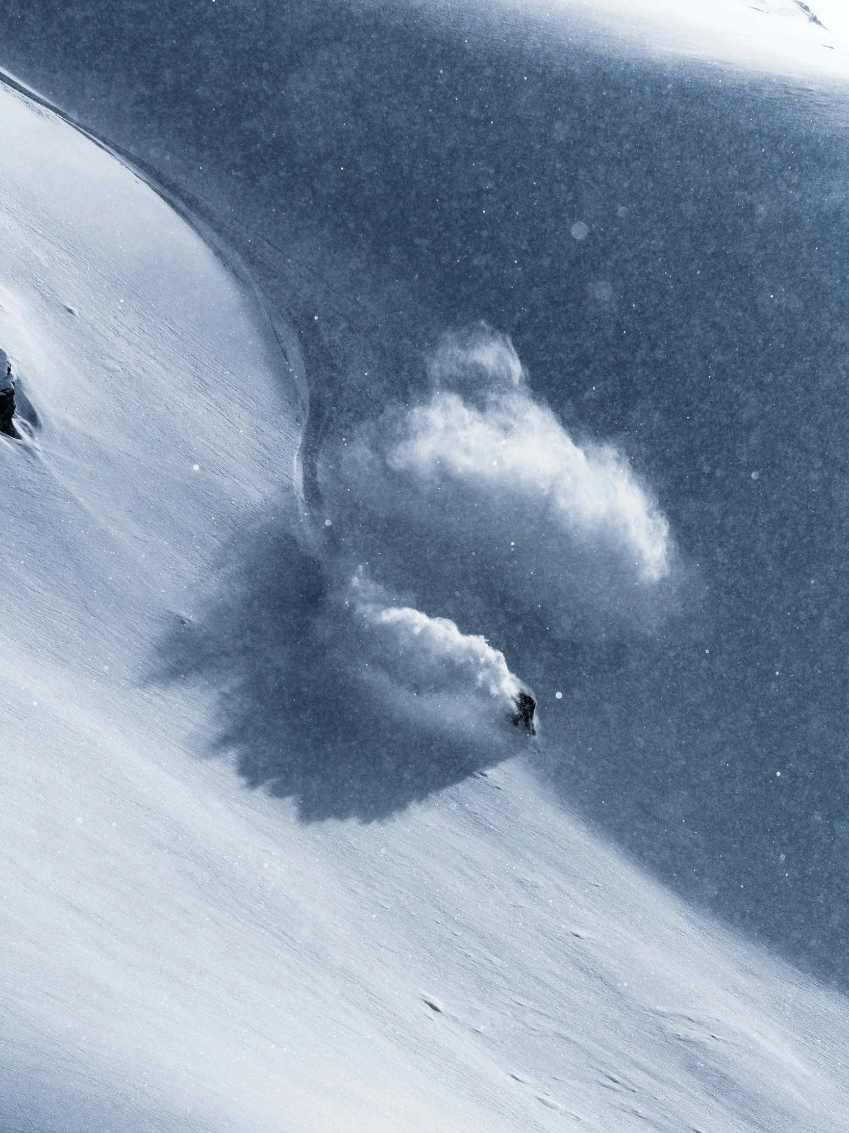 Close-up of a snow-covered mountain slope with visible ski tracks and a cloudy sky.