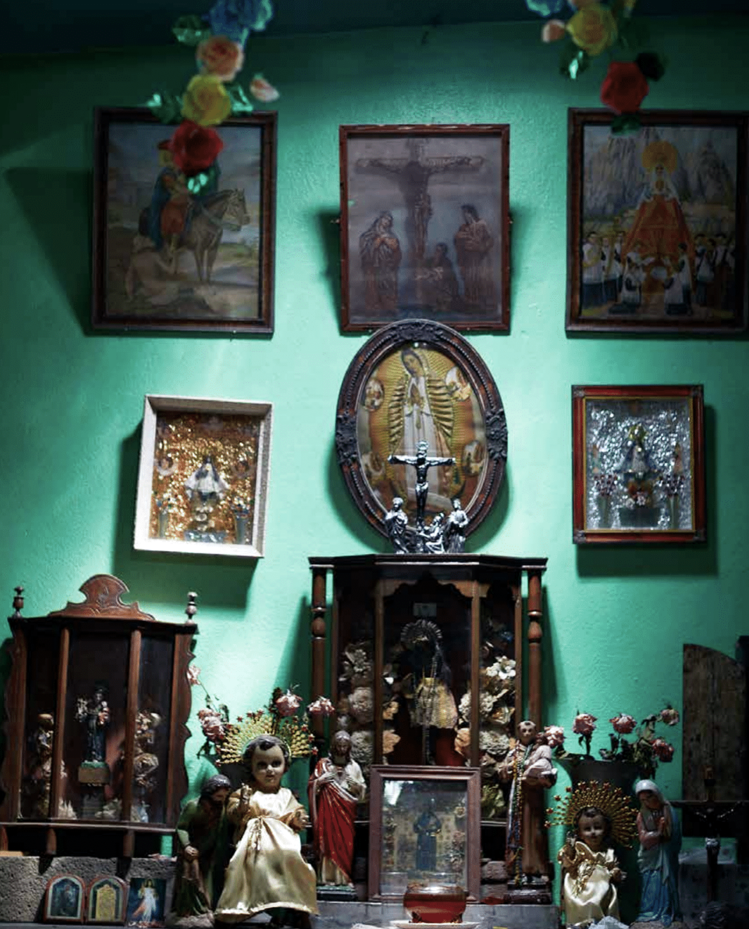 A God with outstretched arms on the crucifix surrounded by religious images and statues in a brightly decorated church altar.