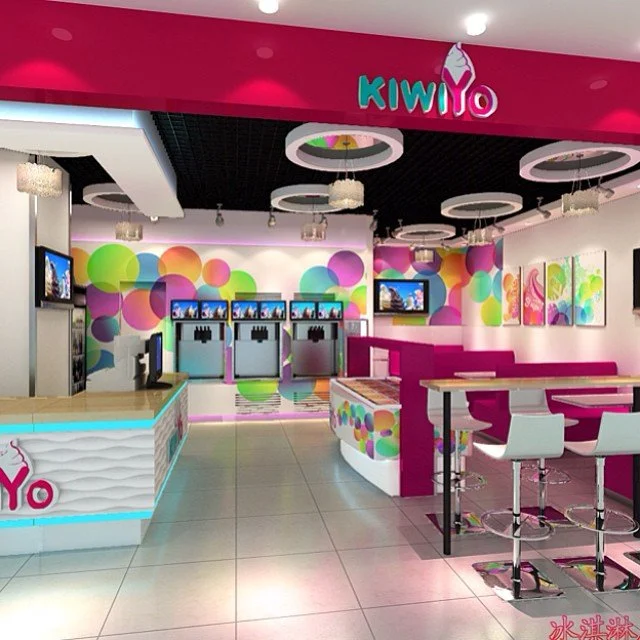 Colorful ice cream shop with pink, purple, and green decor, featuring a counter, seating area, and modern design elements.
