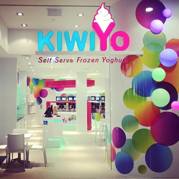 Inside KIWIYO self-serve frozen yogurt shop with colorful decorations and seating area.