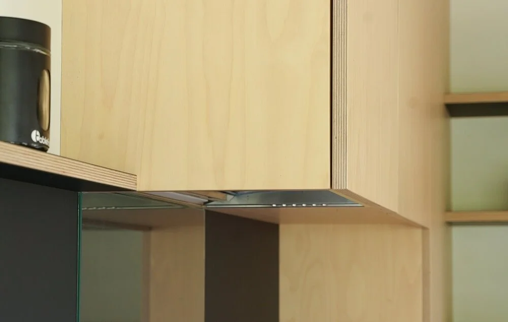 Close-up of light wood kitchen cabinets with a black electronic device on the left