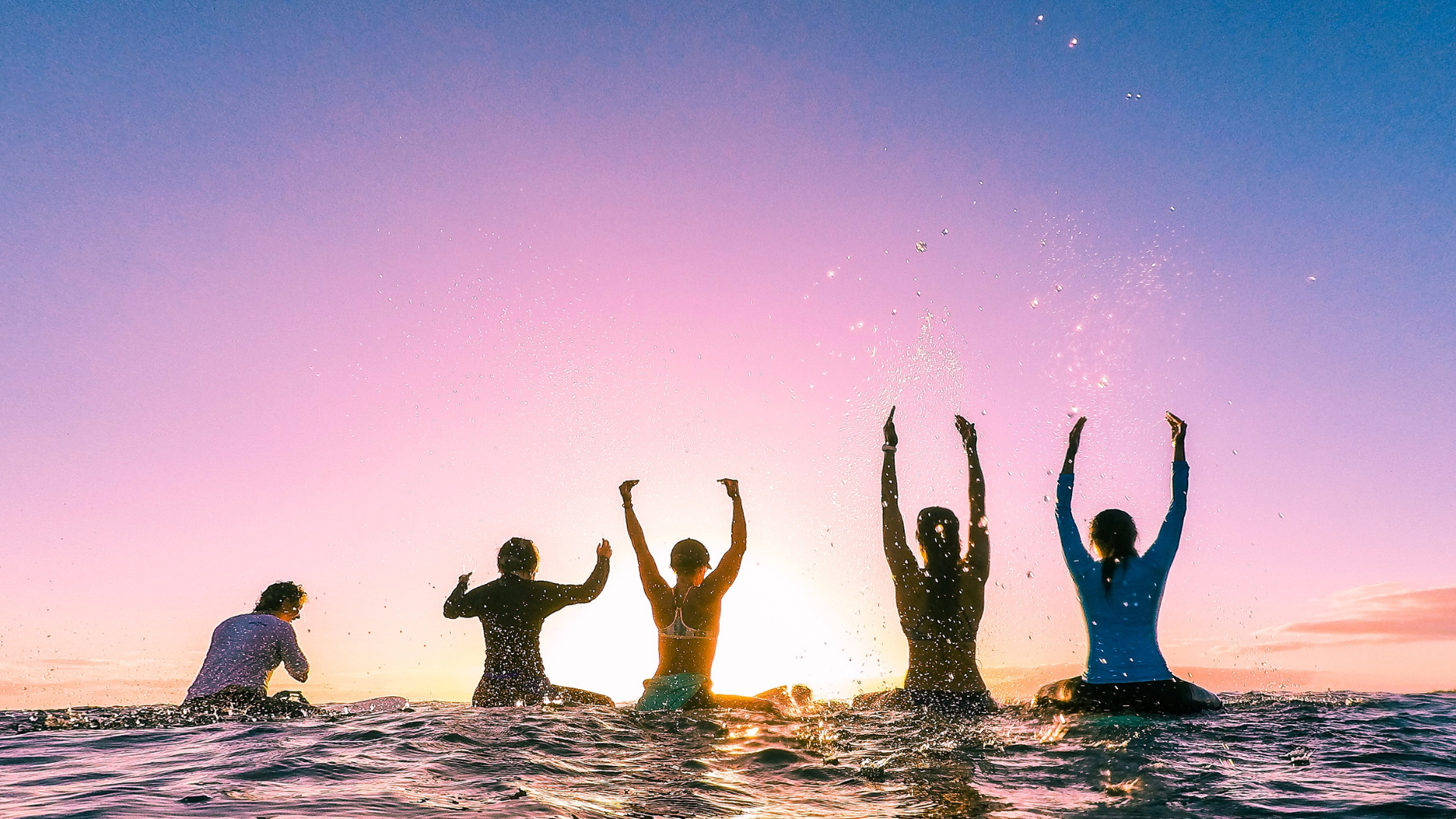 friends having fun at the beach while looking at the sunset