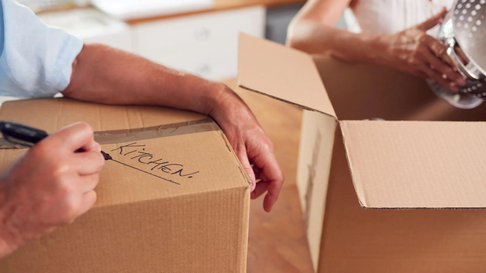 two people putting things in a box to downsize