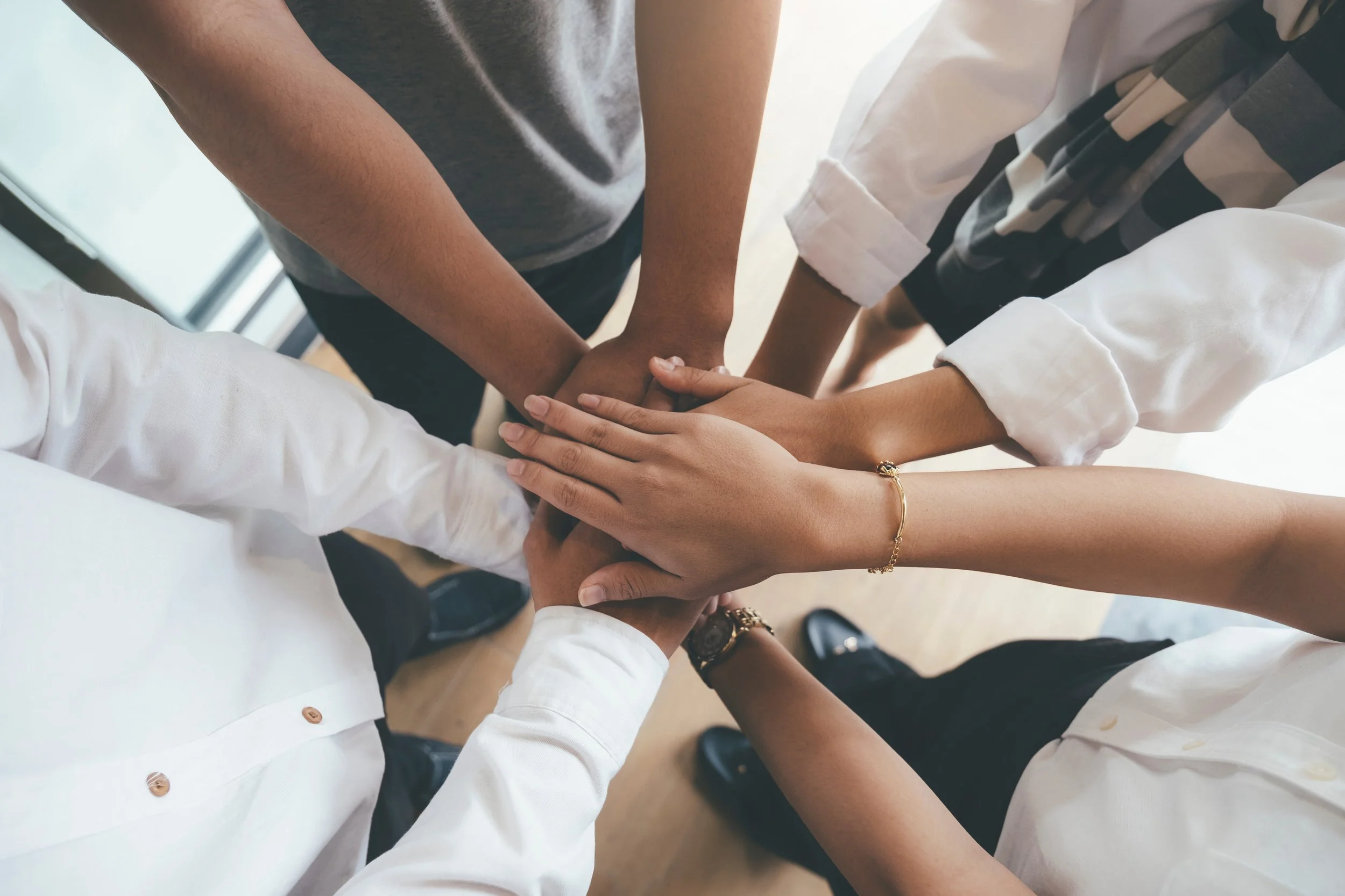 Group of diverse people stacking their hands together in a unity gesture.