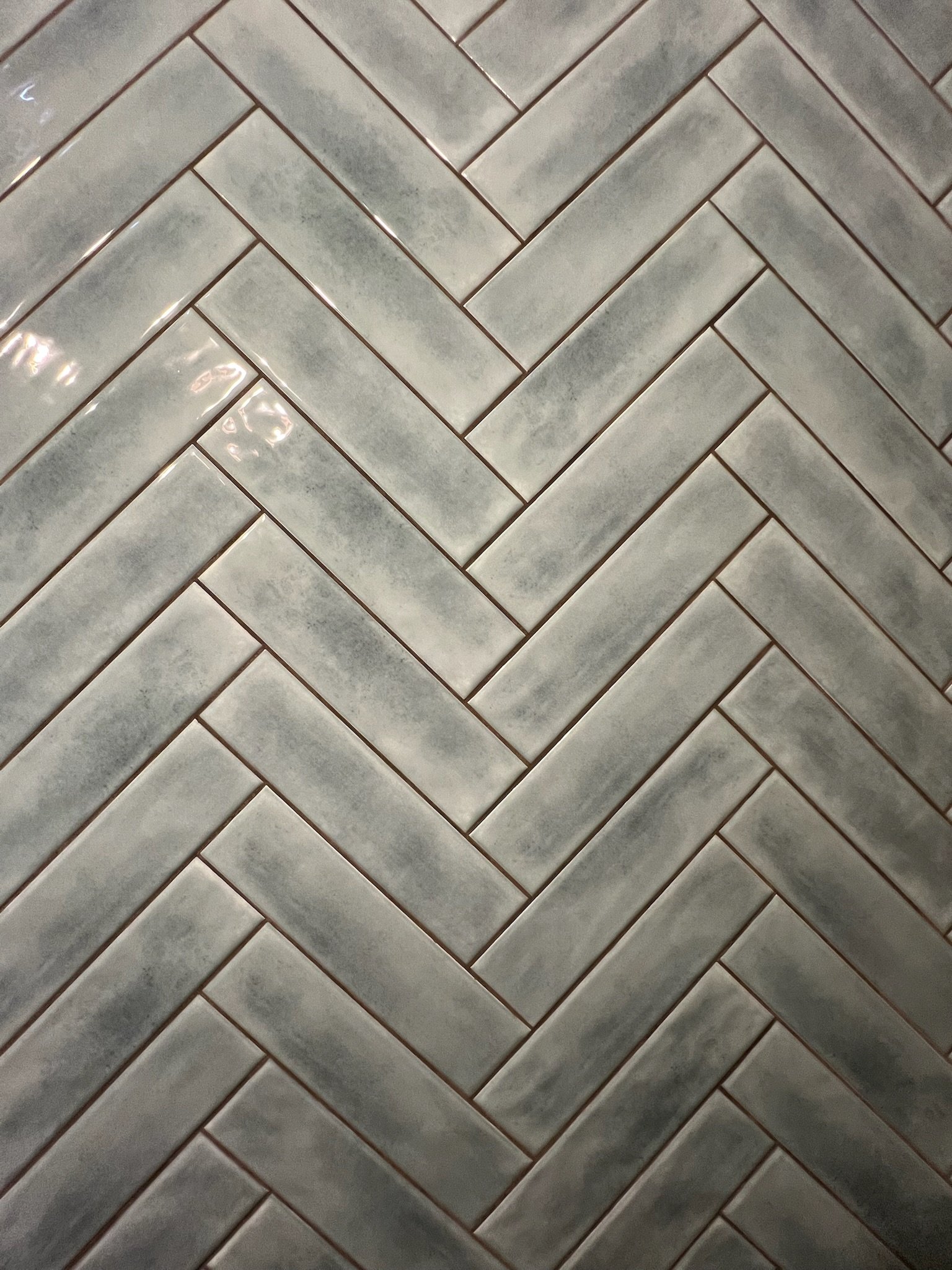 Green herringbone patterned tile floor with a glossy finish.
