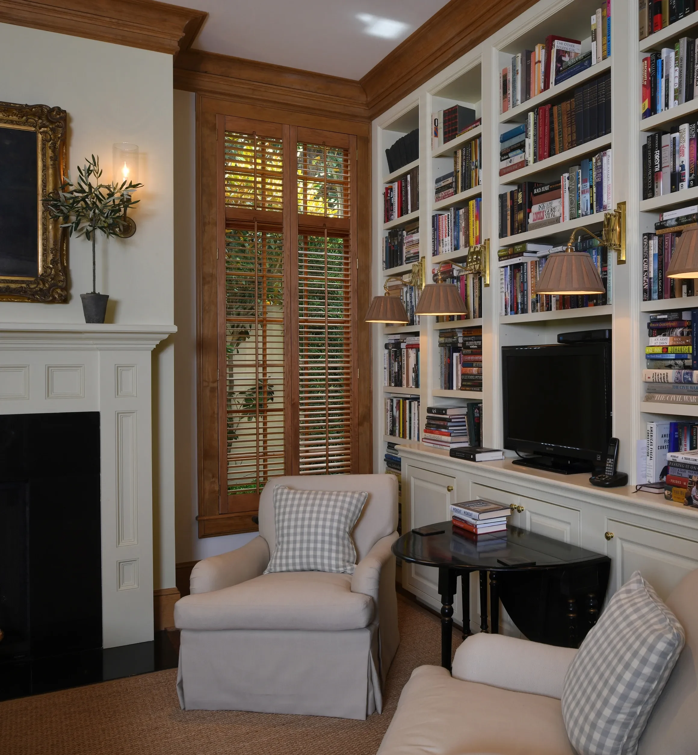 Living room with custom stained wooden shutters stained to match wood trim, 2 1/2" louvers, front tilt rods, divider rails, antique brass hinges, 2 panels hinged left and right.