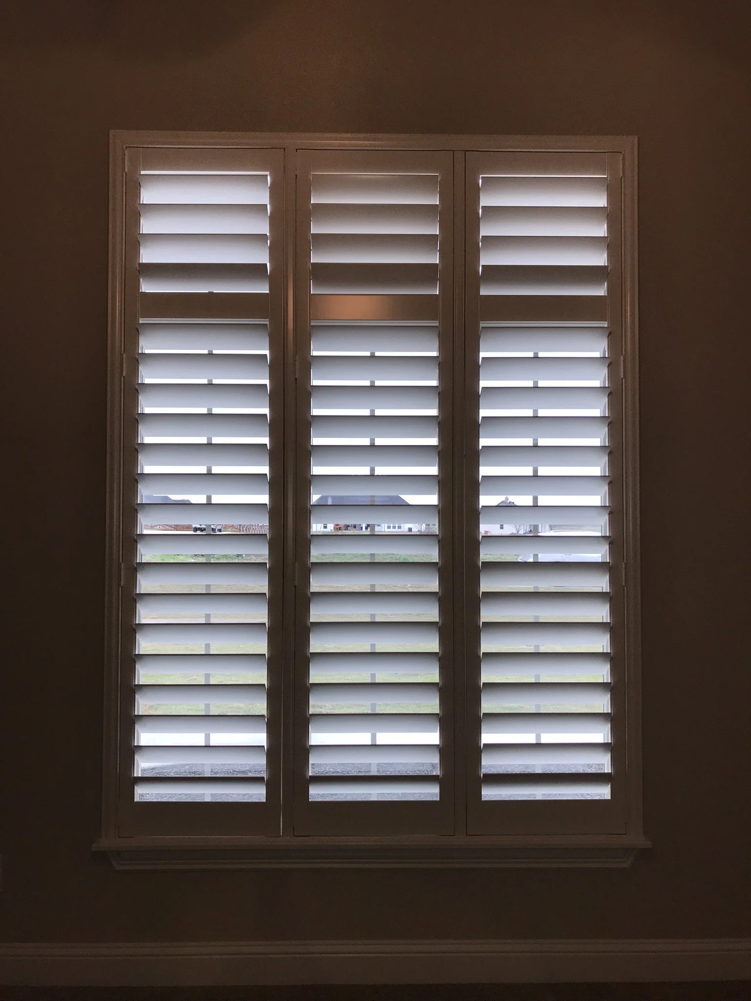 Custom wood shutter with tilt rods, divider rail up high at transom, 4 1/2" louvers, painted to match trim, 3 panel shutter.