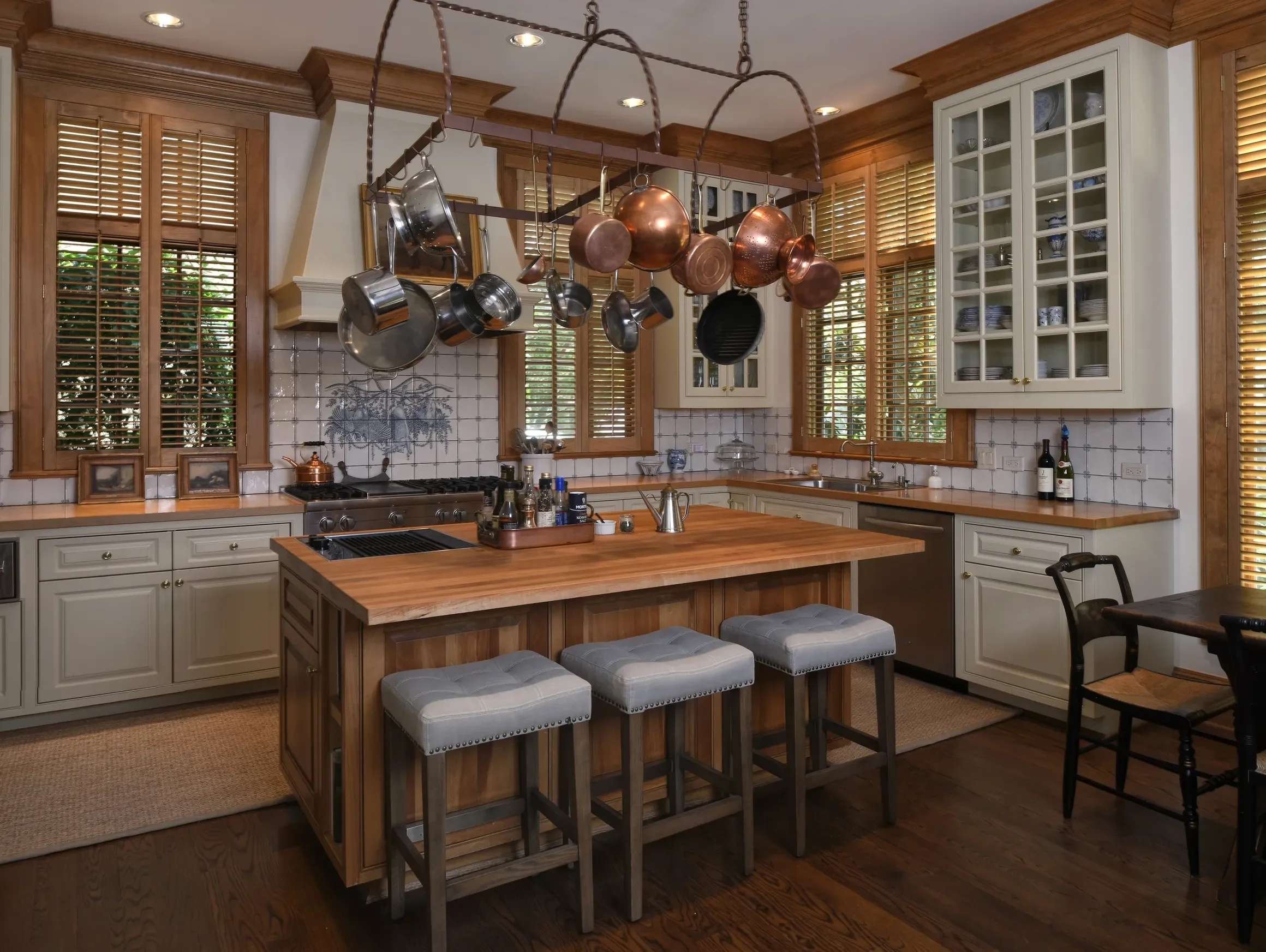 Custom stained wooden shutters stained to match wood trim, 2 1/2" louvers, front tilt rods, divider rails, antique brass hinges, 2 panels hinged left and right.