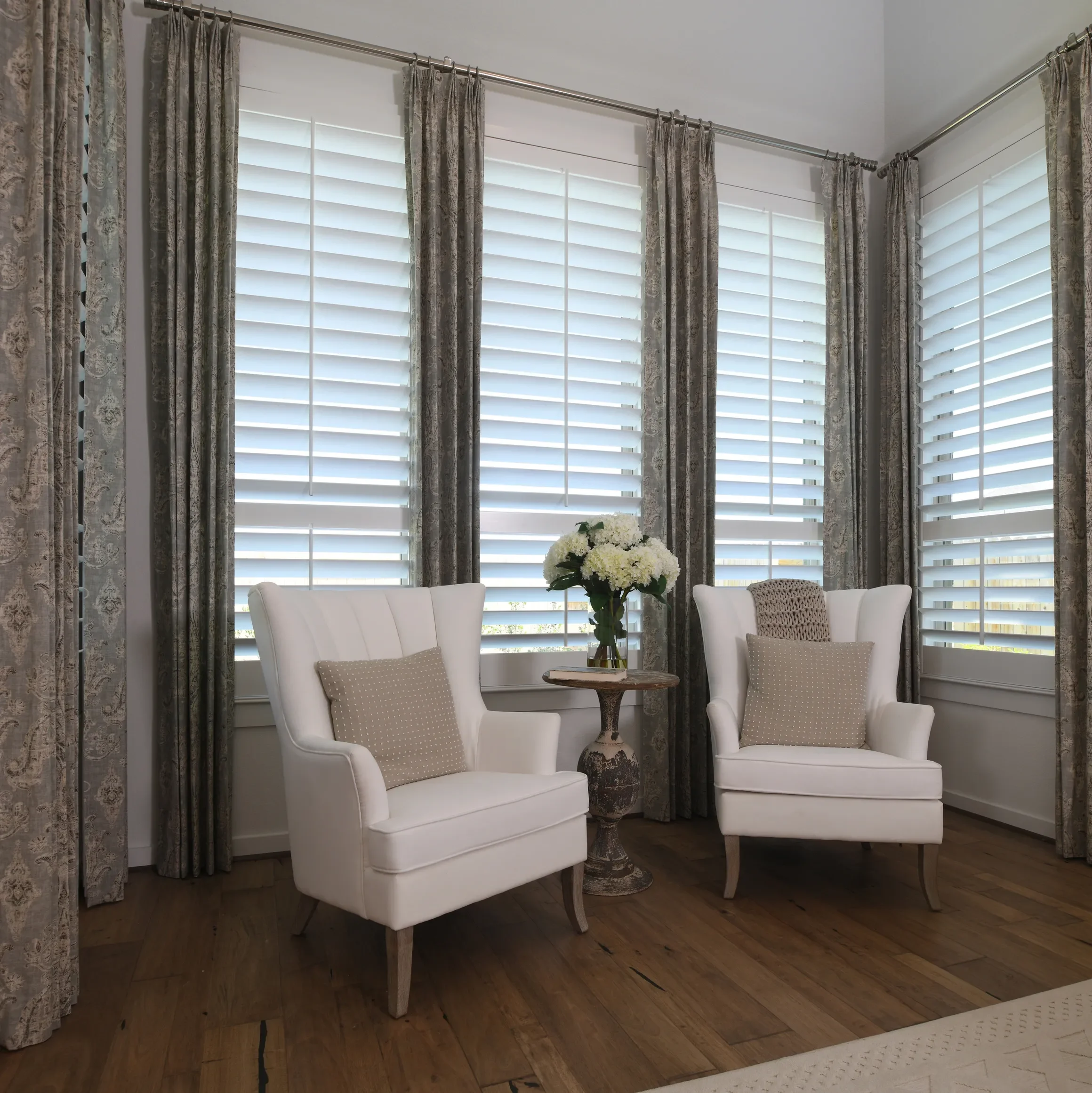 Custom wood shutters with traditional front tilt rod, divider rails at sash, 4 1/2" louvers, painted Sherwin Williams Extra White, painted white hinges.