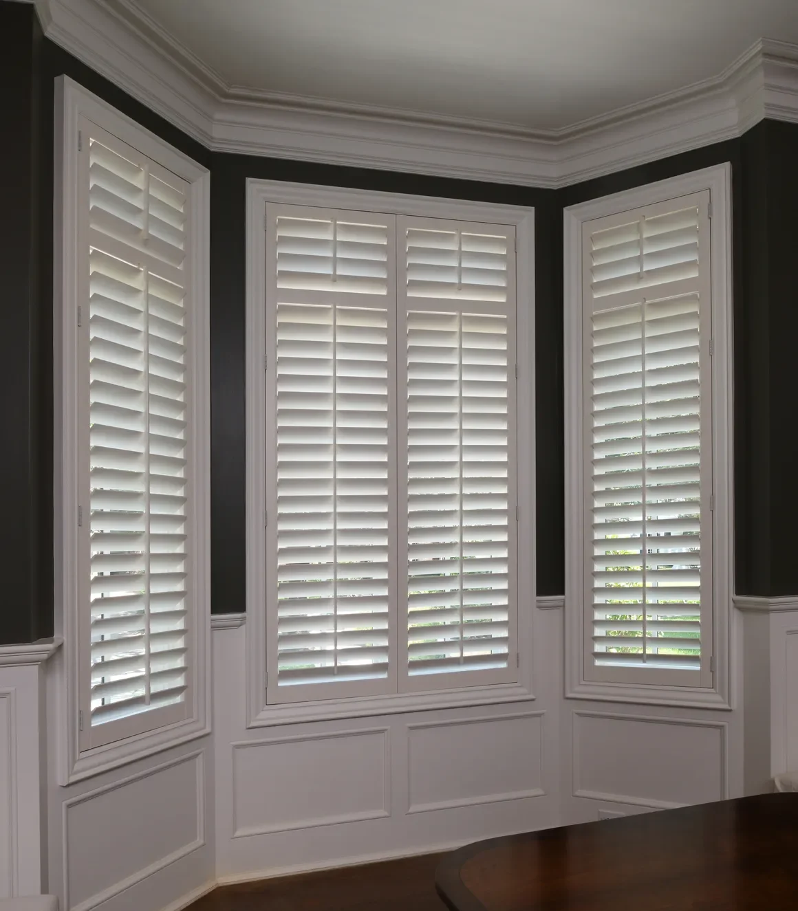 Custom wood shutters with traditional front tilt rod, divider rails at sash, 3 1/2" louvers, painted Sherwin Williams Extra White, painted white hinges.