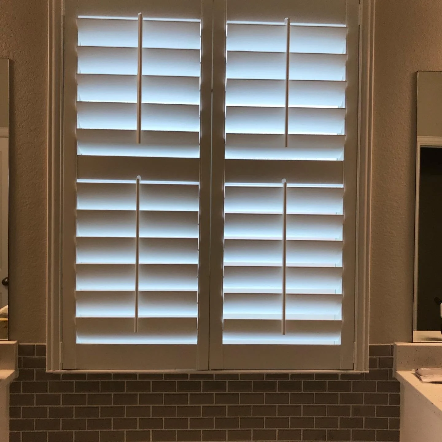 Custom painted wood shutters with front tilt rods, 4 1/2" louvers, divider rail at sash, painted white.  2 panels hinged left, right.