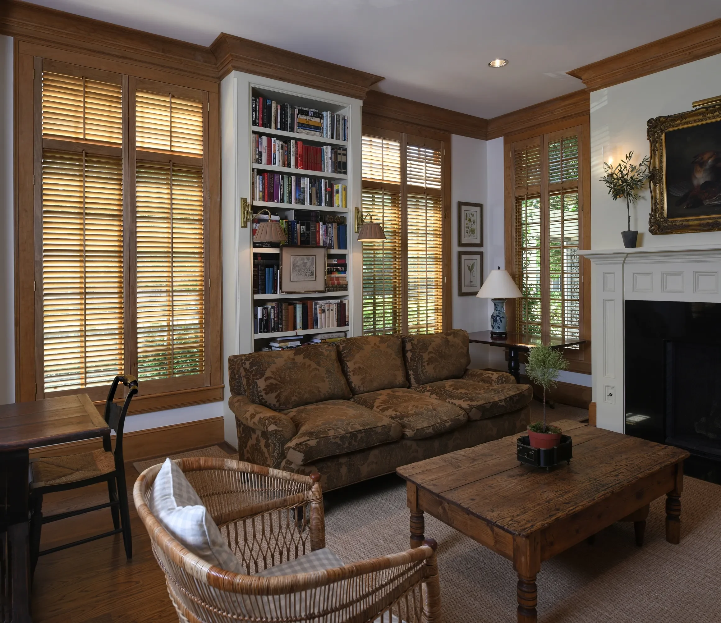 Living room with custom stained wooden shutters stained to match wood trim, 2 1/2" louvers, front tilt rods, divider rails, antique brass hinges, 2 panels hinged left and right.