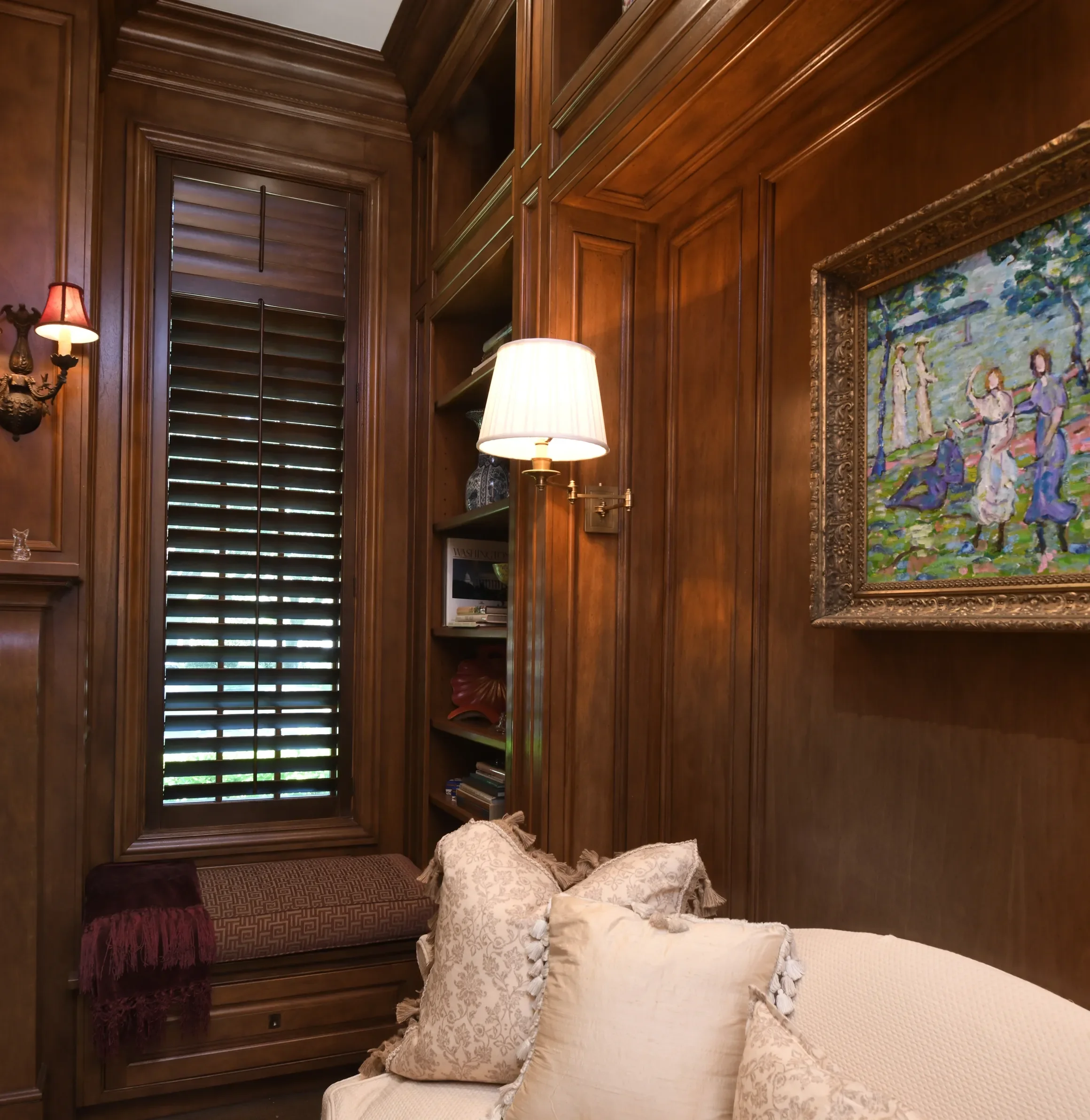 Study with custom stained wooden shutters stained to match wood trim, 2 1/2" louvers, front tilt rods, divider rails, antique brass hinges, 2 panels hinged left and right.