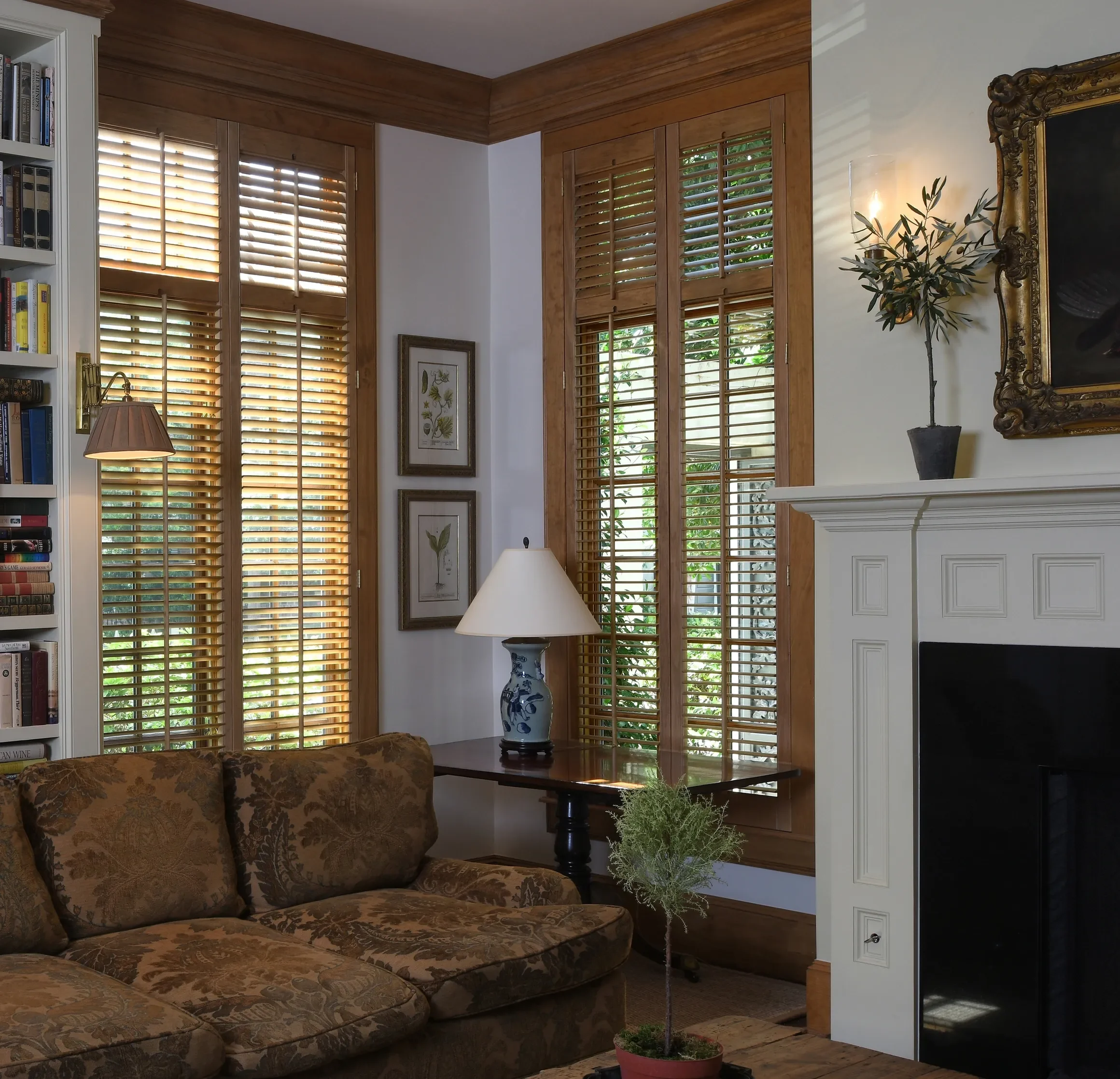 Living room with custom stained wooden shutters stained to match wood trim, 2 1/2" louvers, front tilt rods, divider rails, antique brass hinges, 2 panels hinged left and right.
