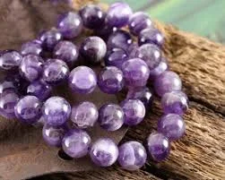 Purple beaded bracelet resting on a piece of wood.