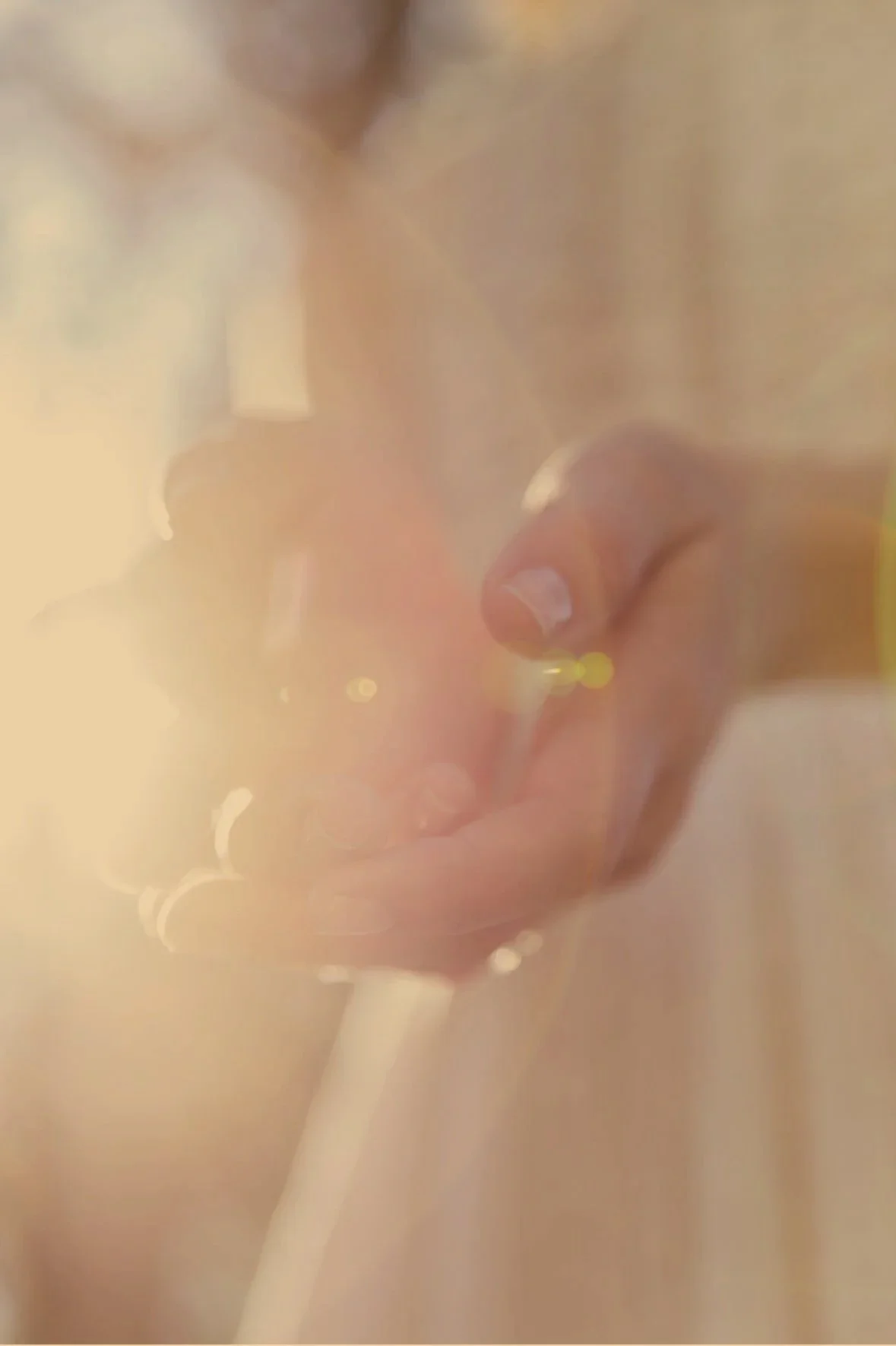Close-up of a person's open hands with energy inside, with warm yellow and orange lighting creating a soft, hazy effect.